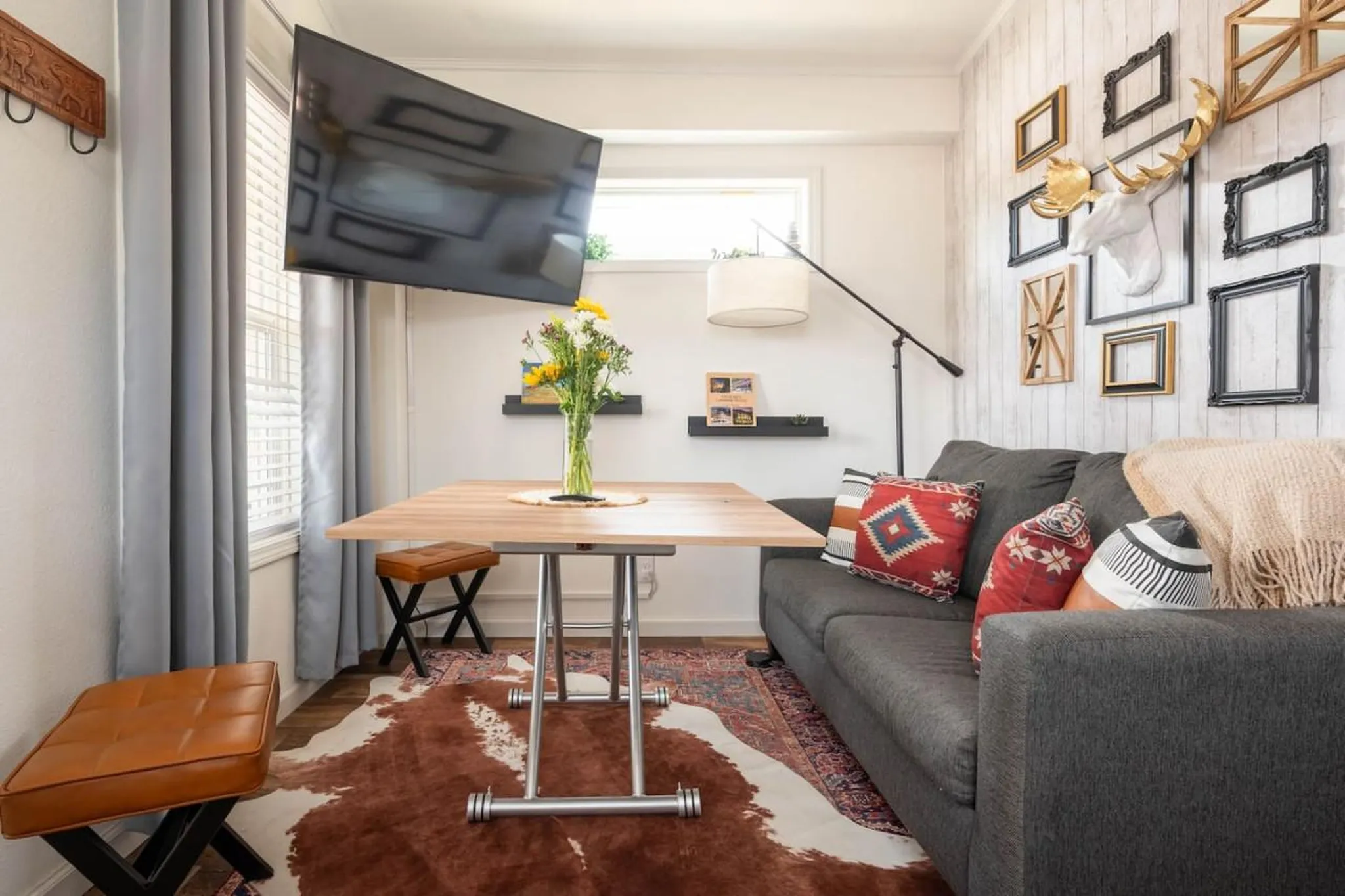 A cozy living area with a sofa, dining table, and mounted TV.