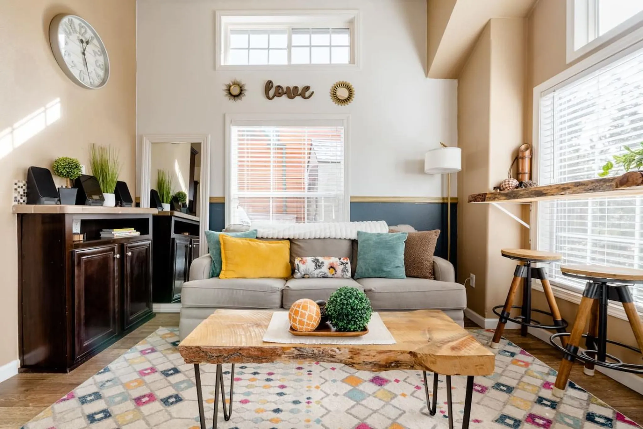 Living room with a grey couch, colorful rug, and wooden coffee table.