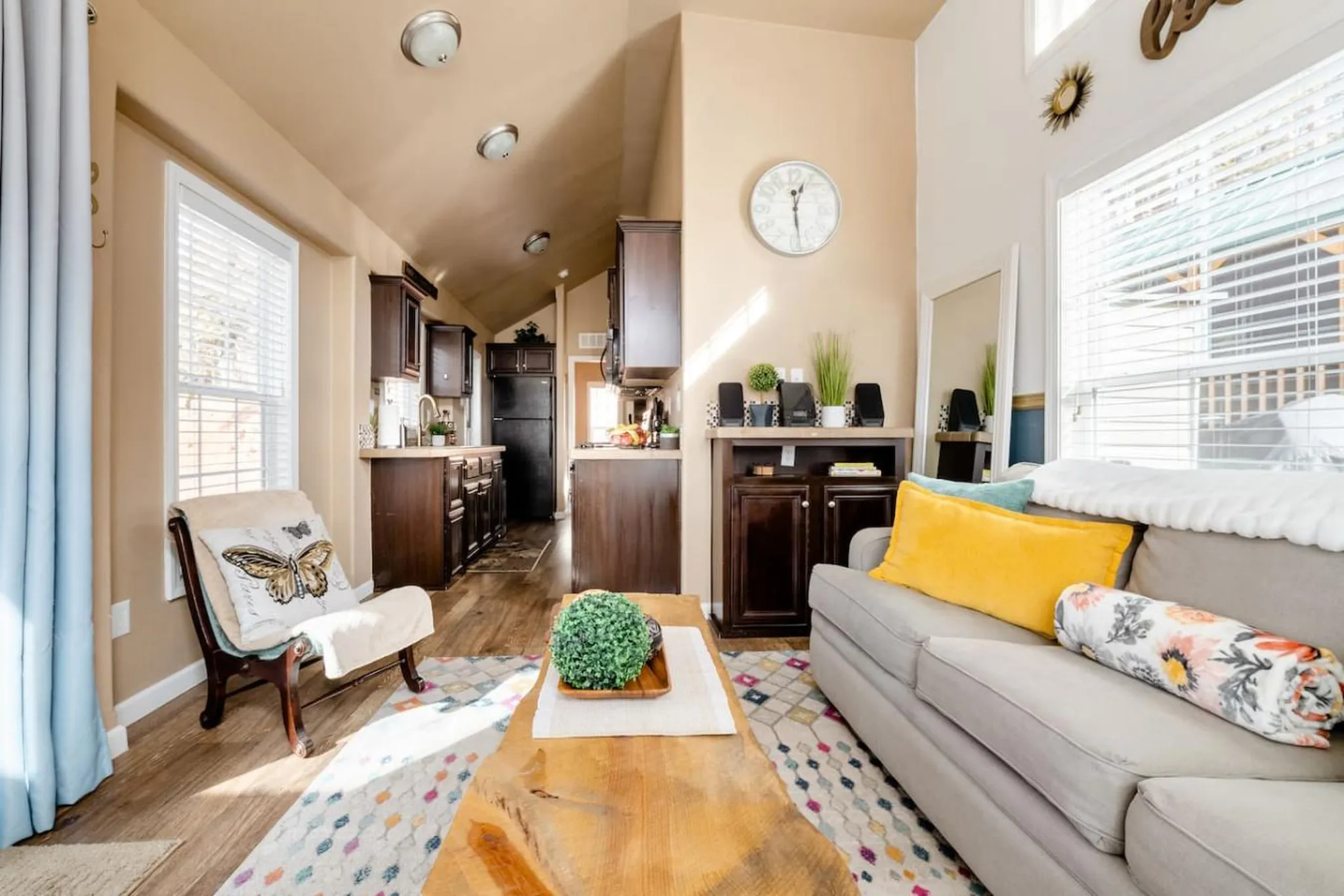 Living room with a couch, armchair, and kitchen in the background.