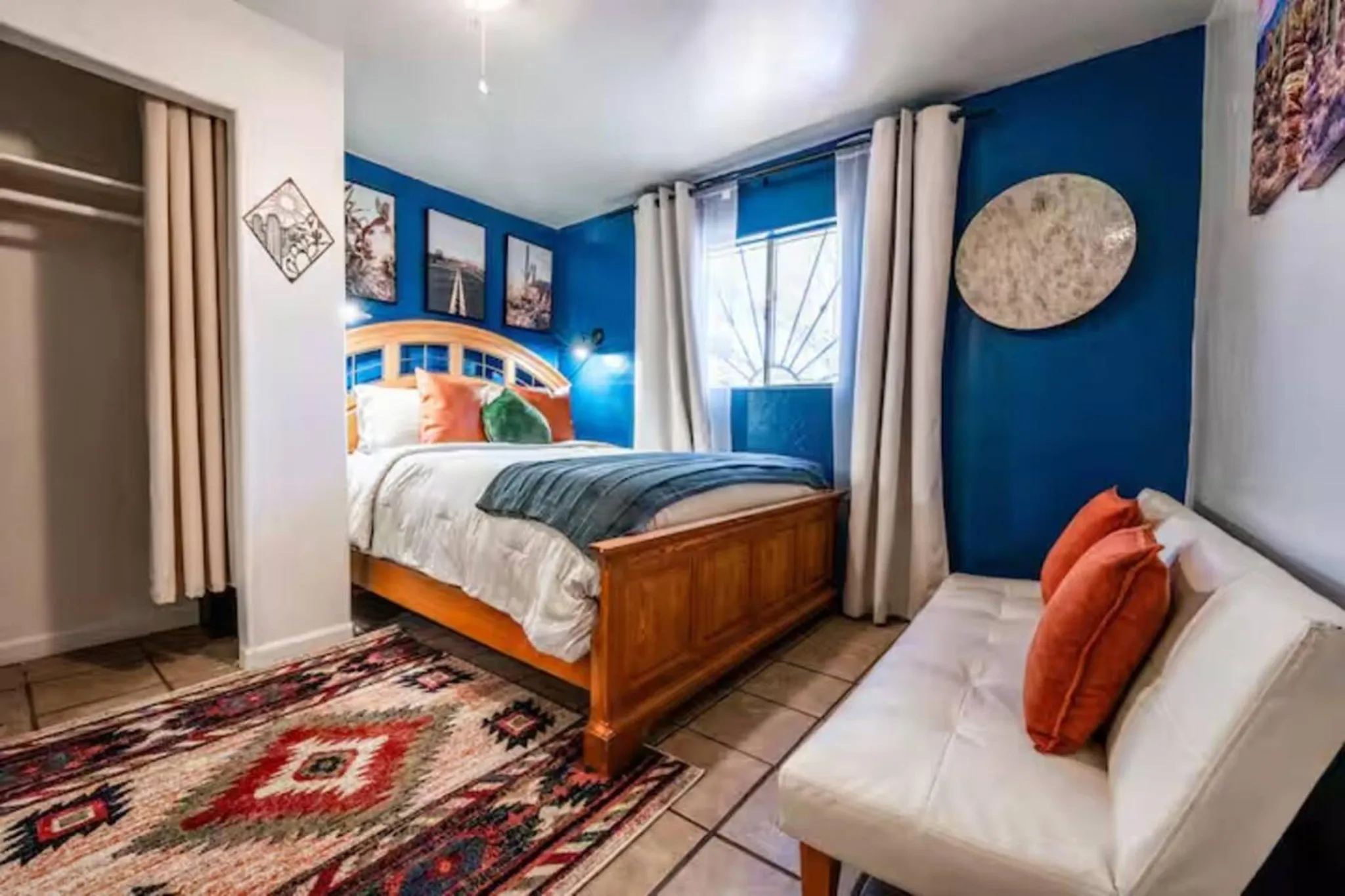 Bedroom with a queen bed, blue walls, and a colorful rug.