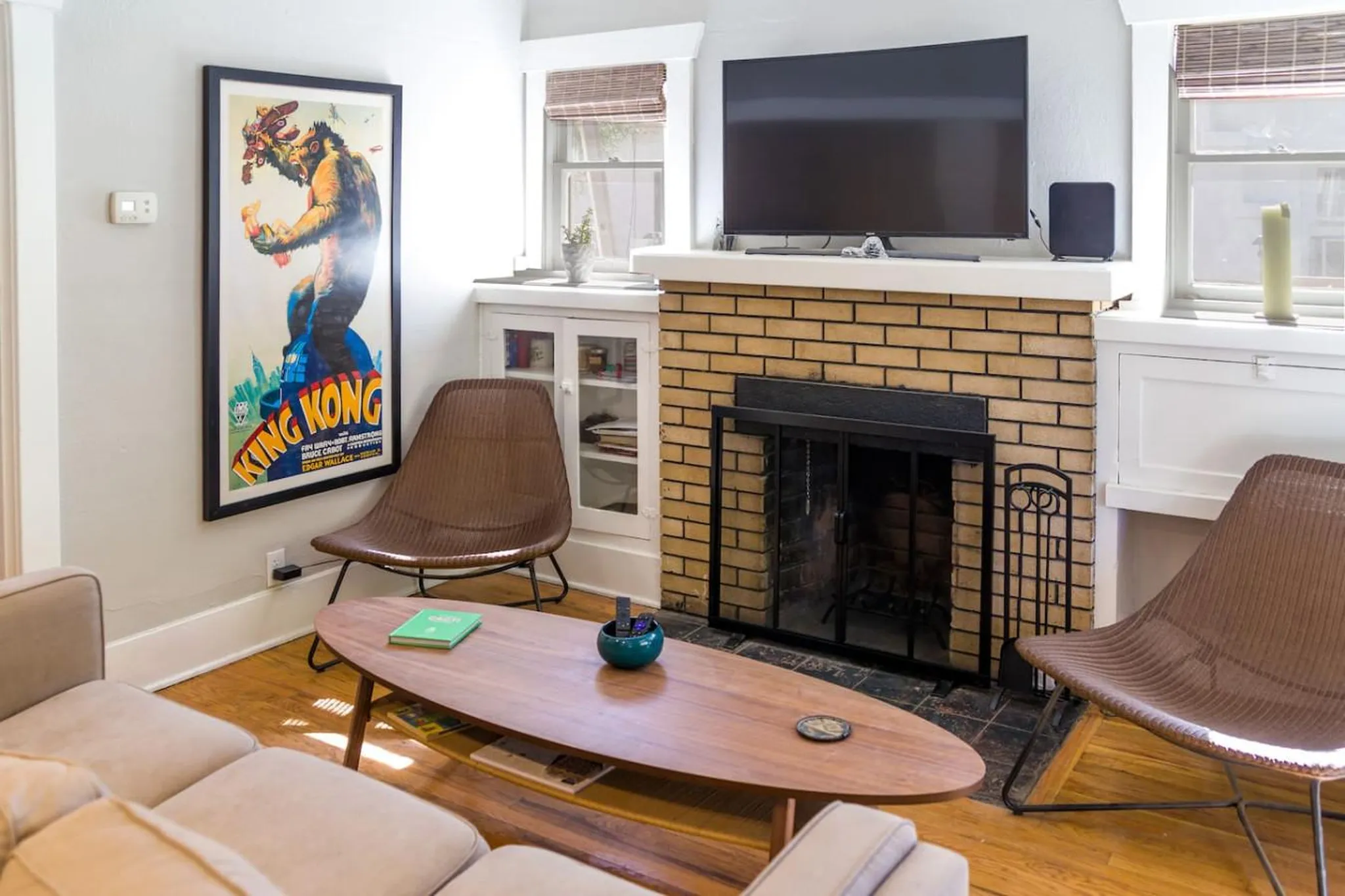 A living room with a fireplace, King Kong poster, and two modern chairs.