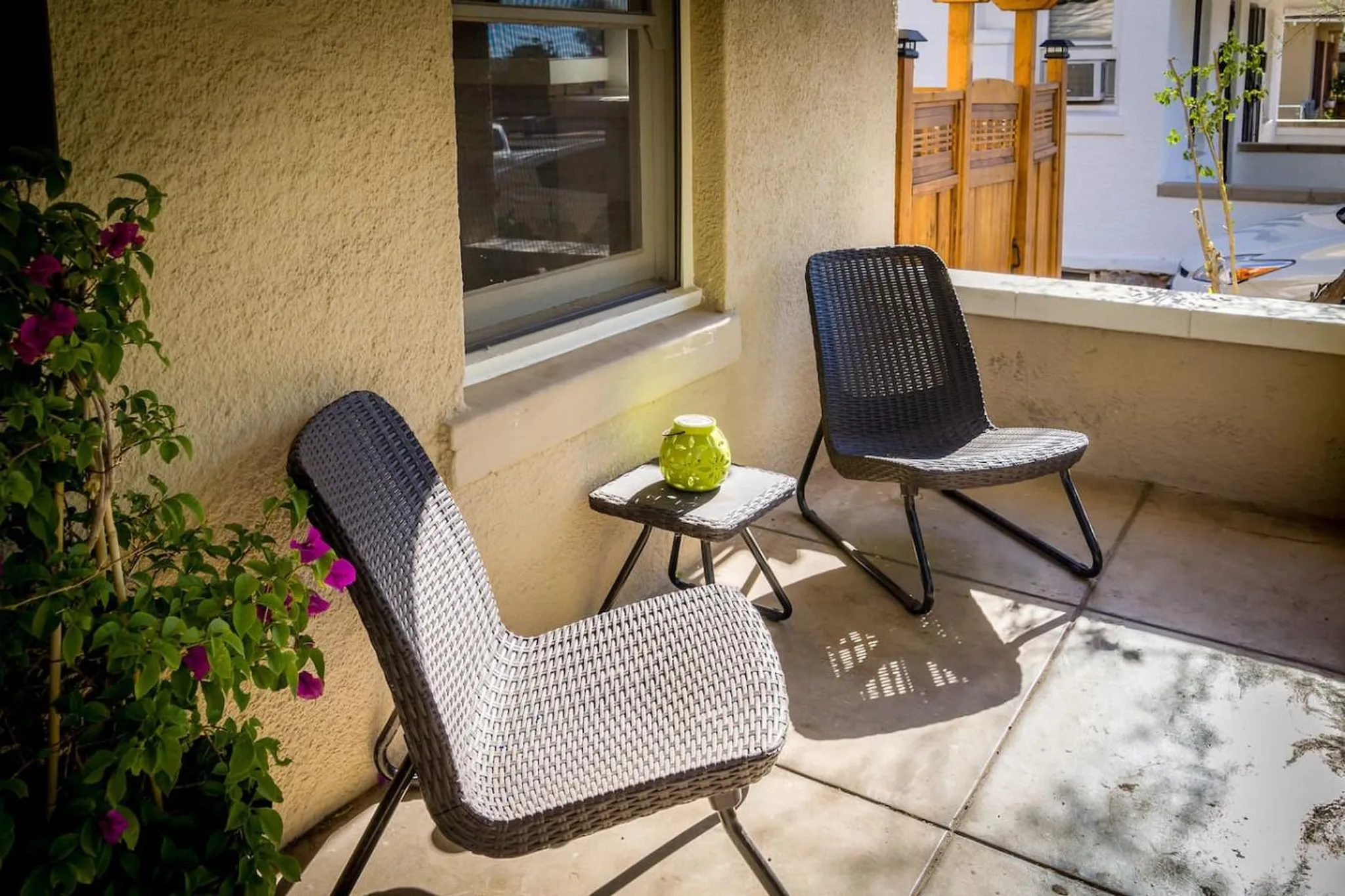 Chairs and a small table with a green lantern on a patio.