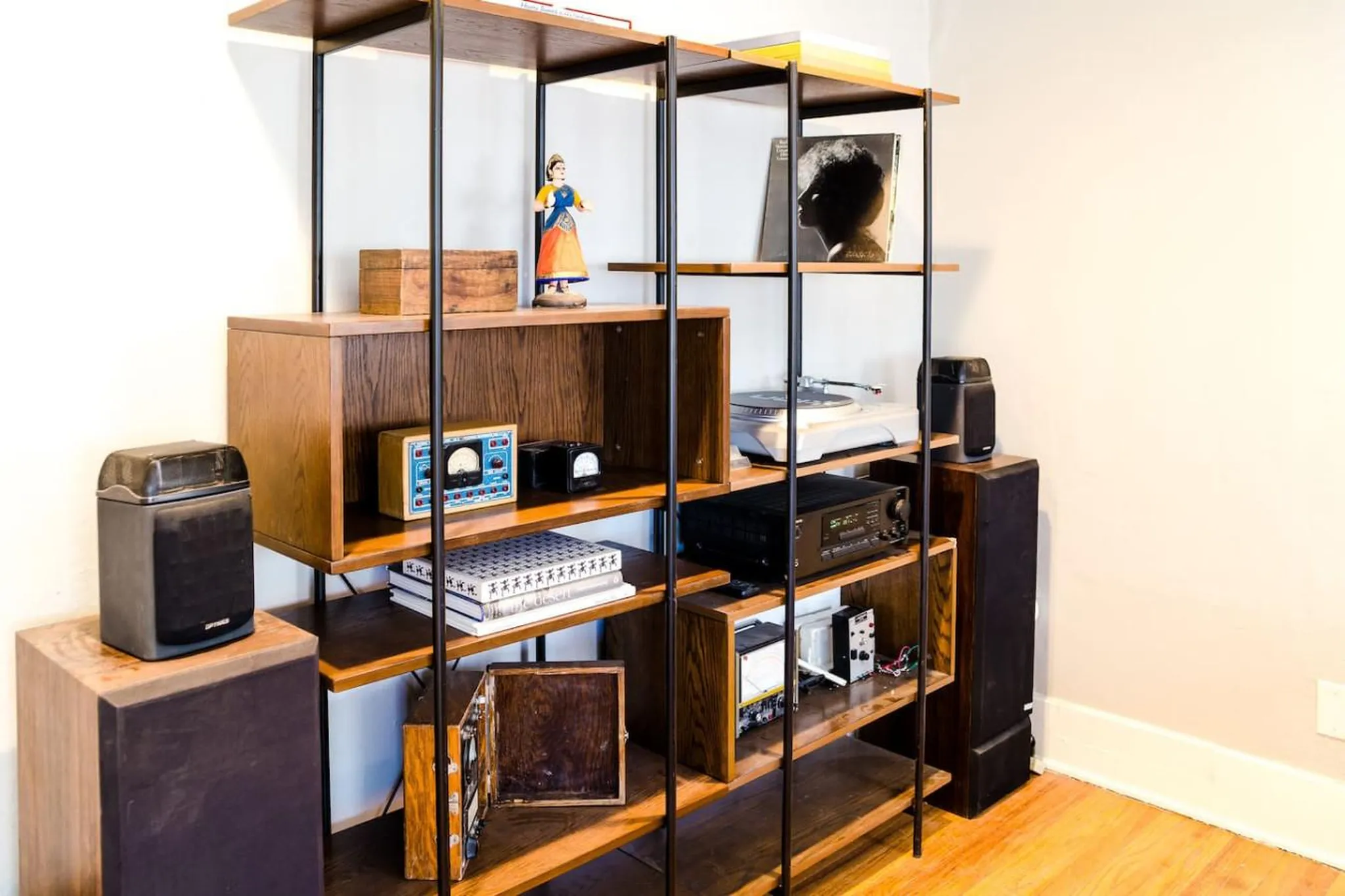 Wooden shelf unit with vintage audio equipment, records, and decorative items.