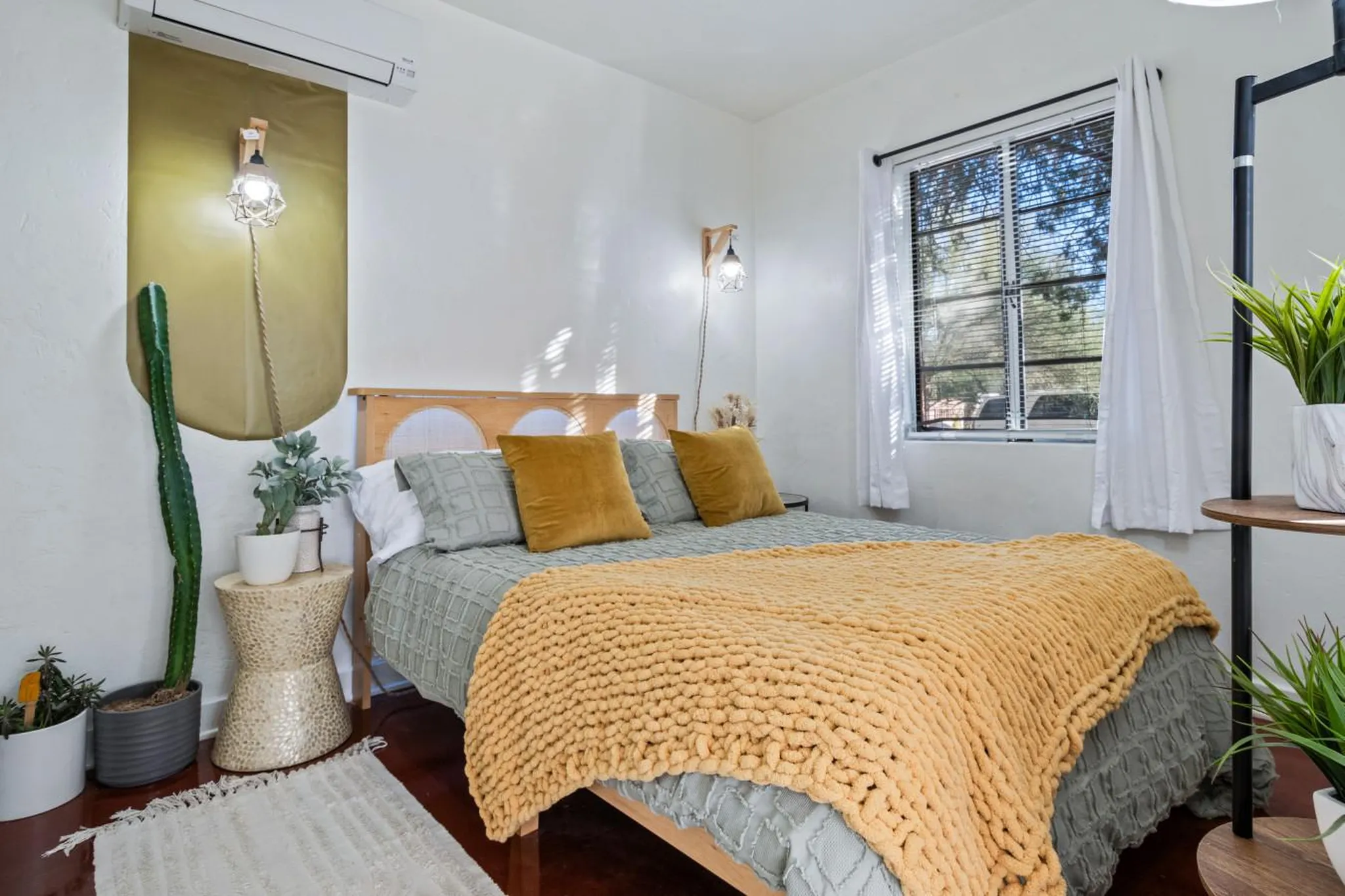 A boho-chic bedroom with a cactus, plants, and a cozy bed.