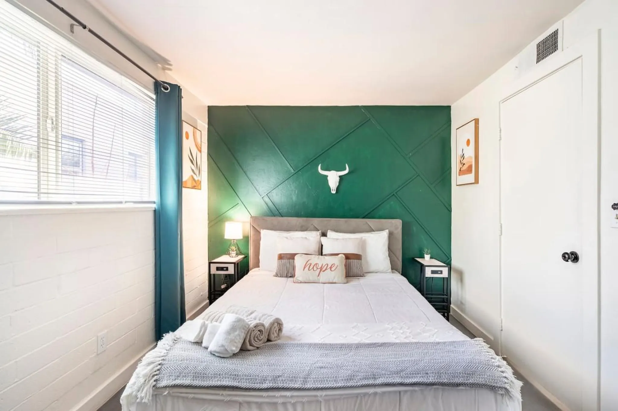 Bedroom with a green geometric accent wall and a bull skull decoration.
