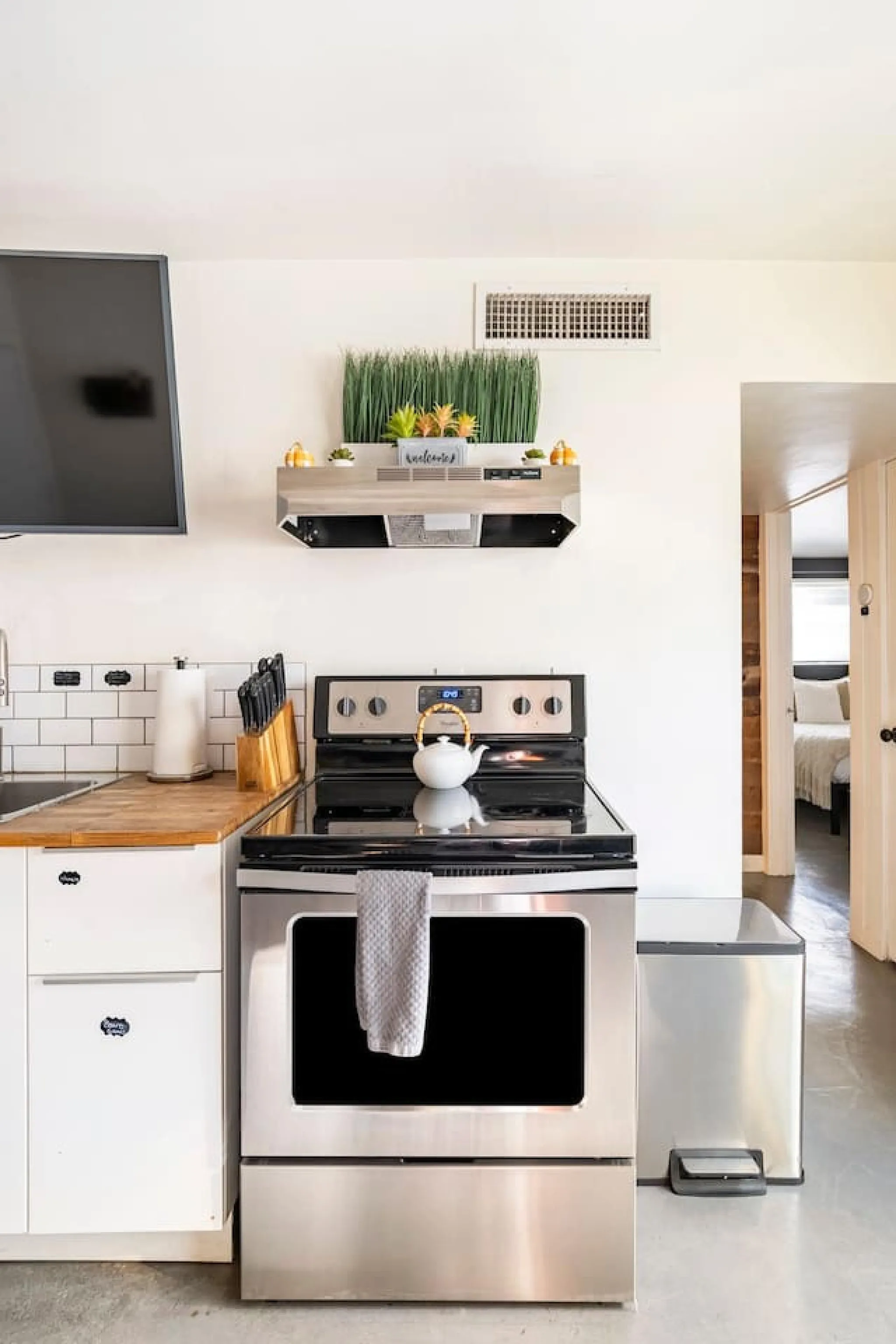 A modern kitchen with stainless steel appliances, a wooden countertop, and a trash can.