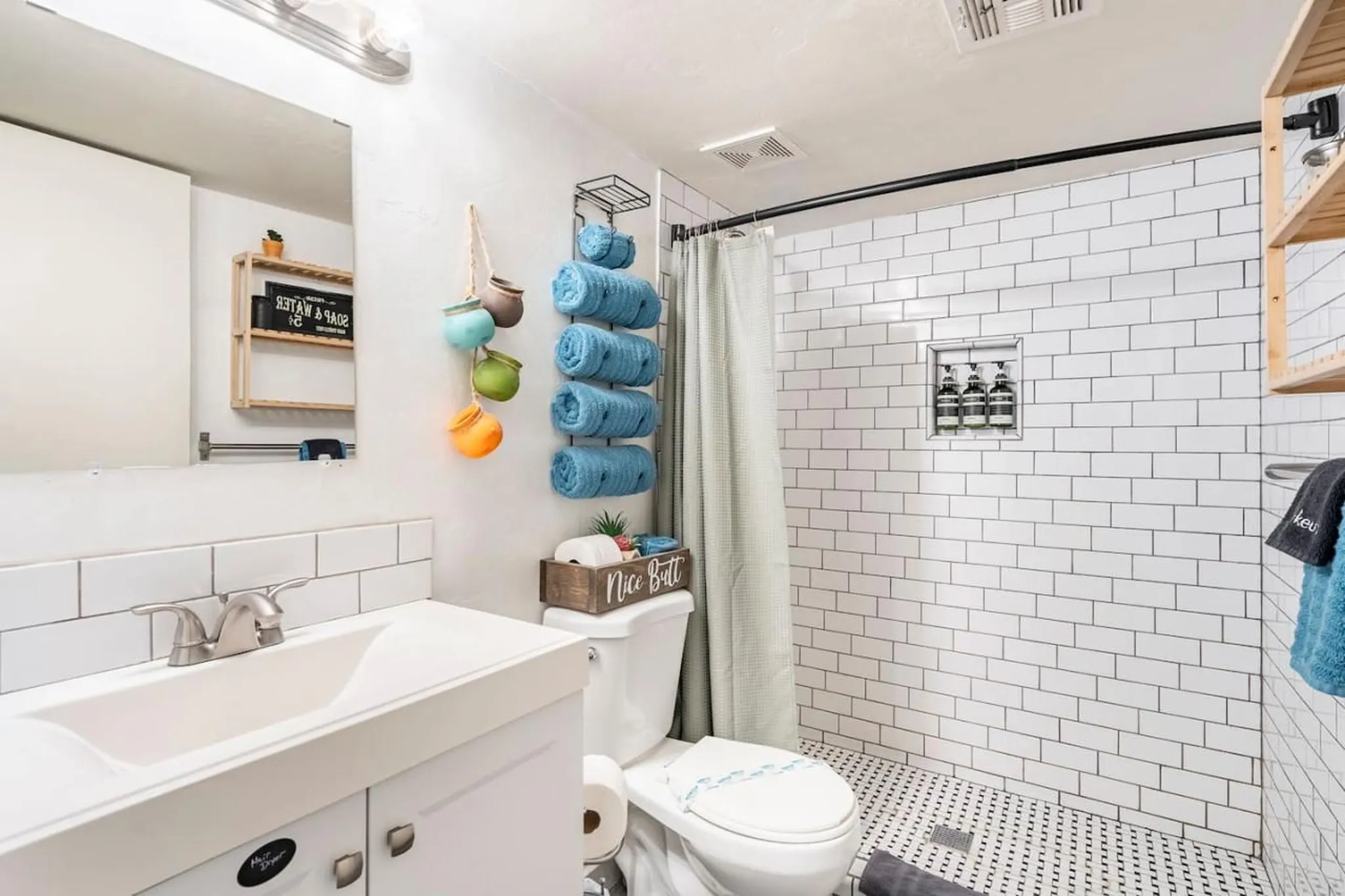 A modern bathroom with white subway tile, a sink, toilet, and shower.