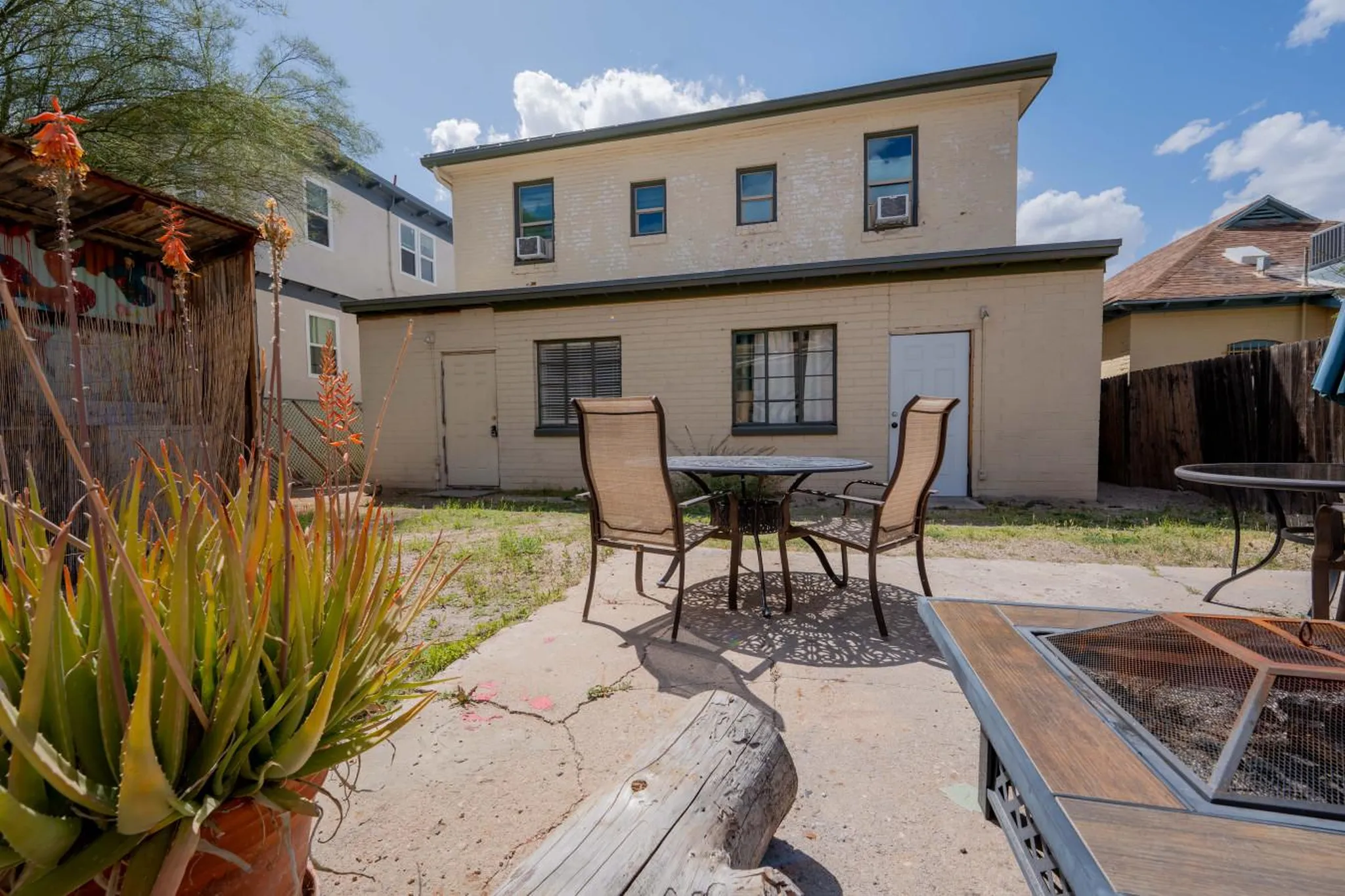 Outdoor patio with a table and chairs, fire pit, and aloe vera plants.