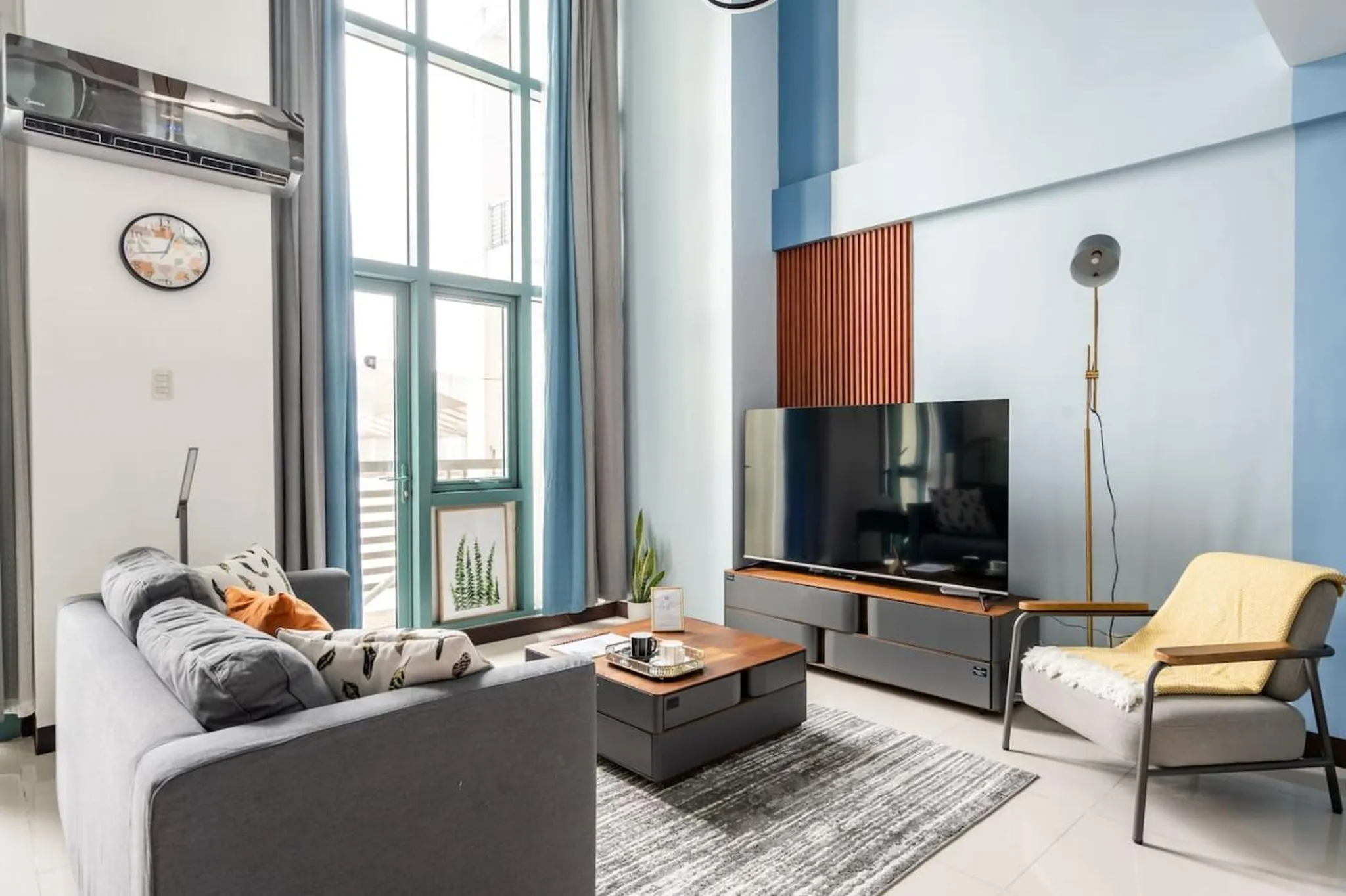A living room with a gray sofa, coffee table, TV, and armchair.