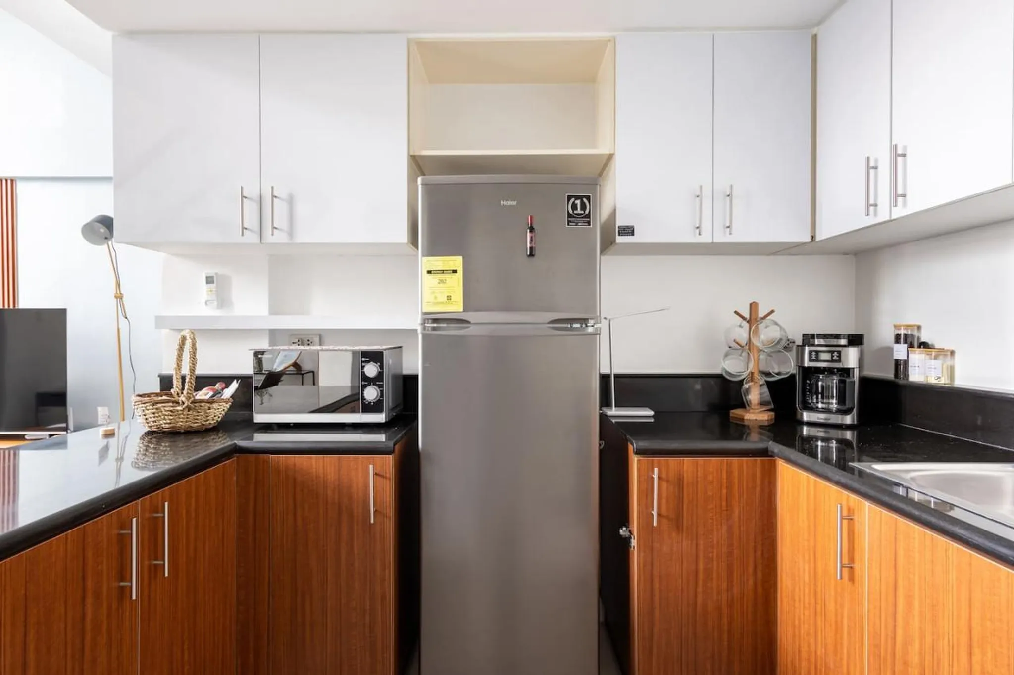 A modern kitchen with a silver refrigerator, microwave, and coffee maker.