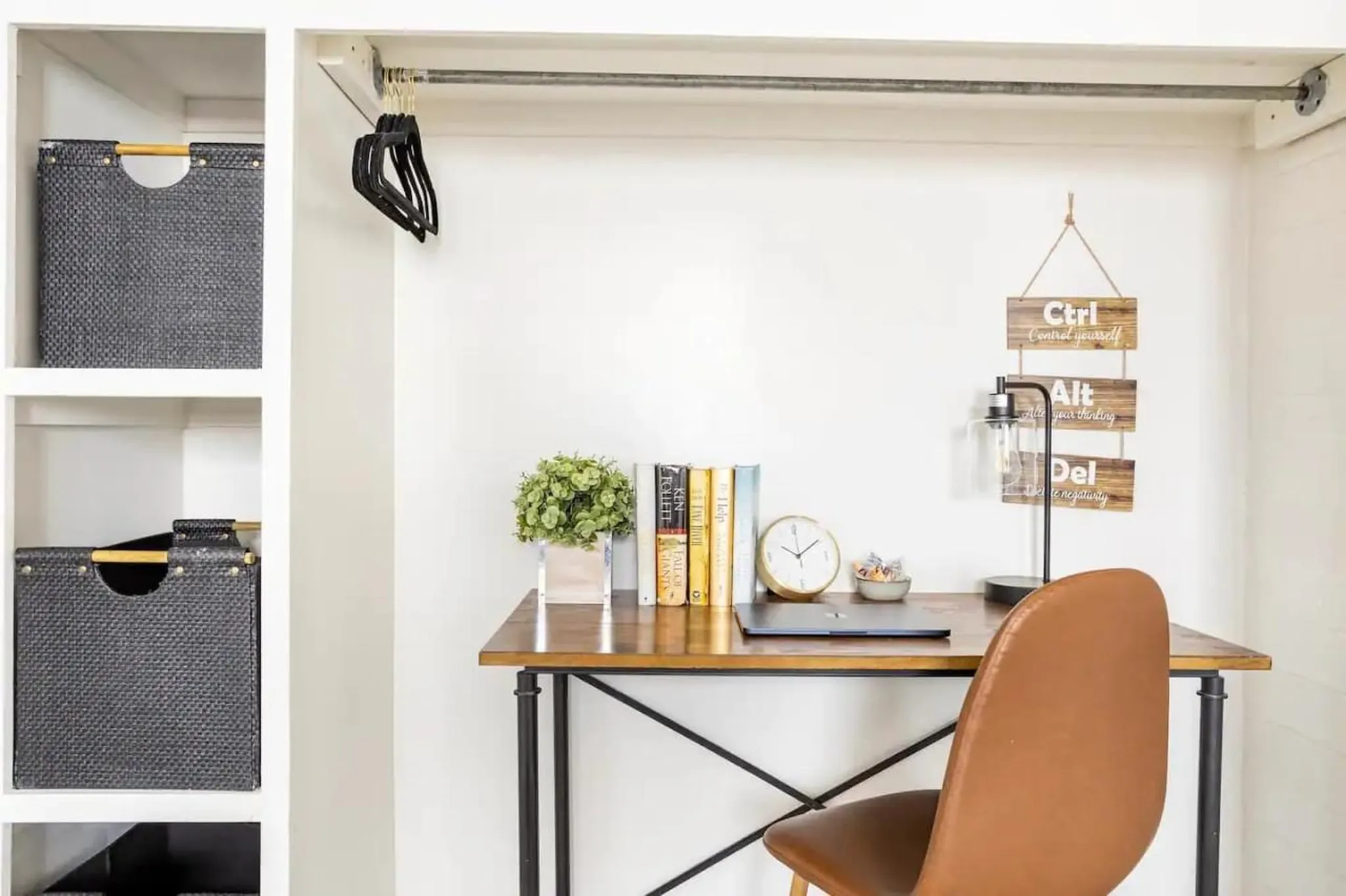 A closet turned into a home office with a desk, chair, and storage bins.