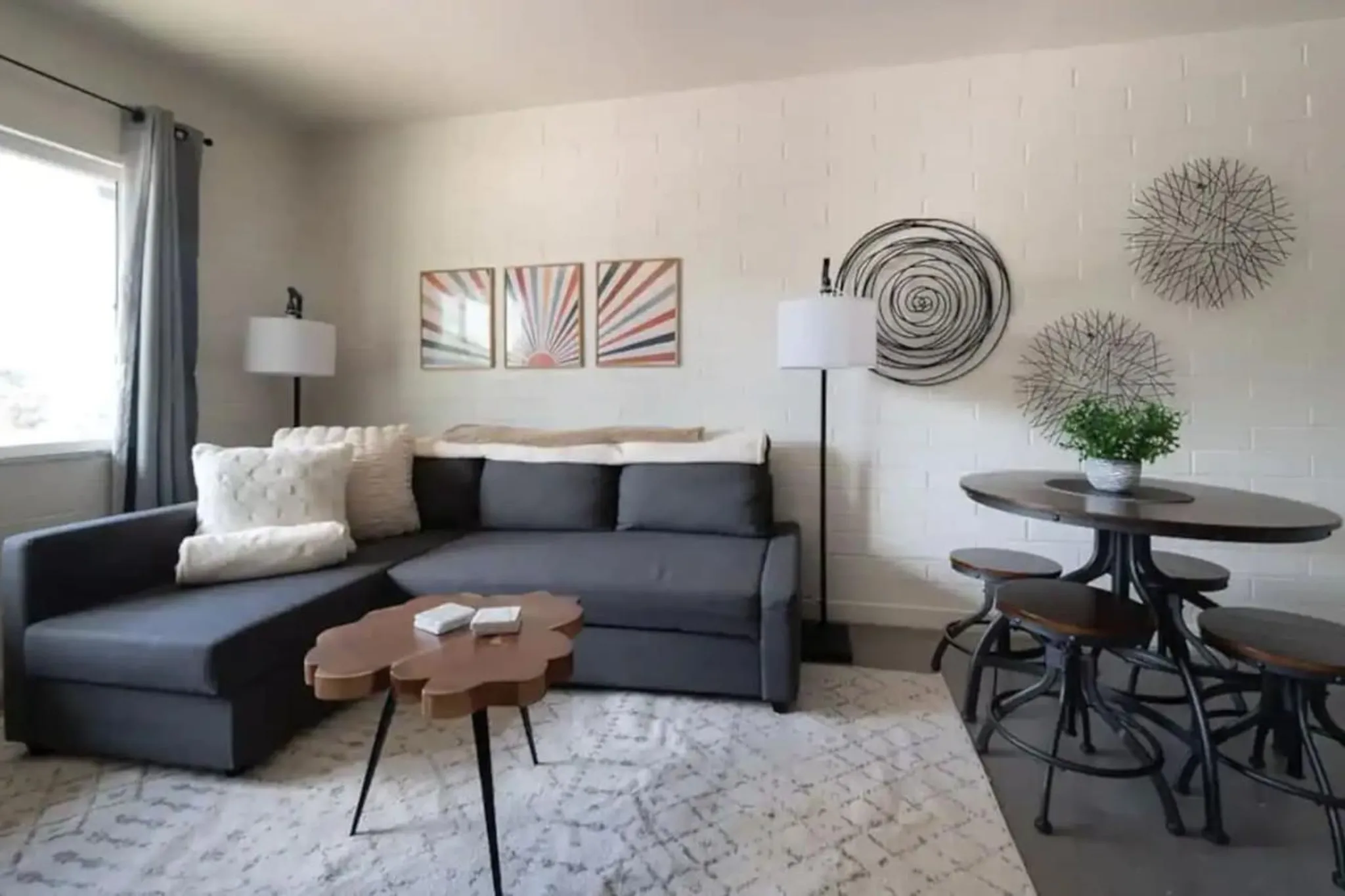 A sectional sofa and a wooden table with stools are in a living room.