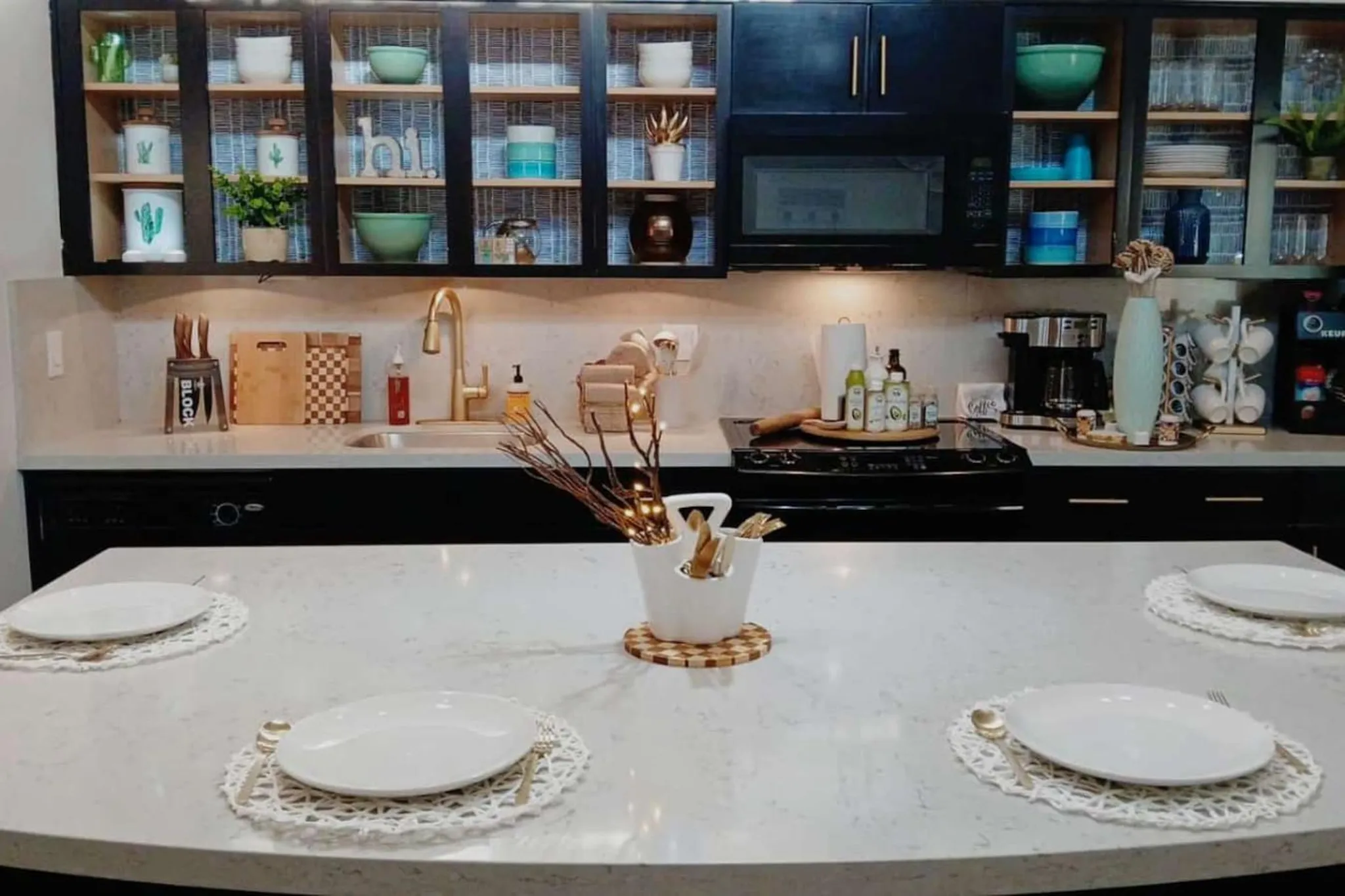 A kitchen island with plates set for a meal, with cabinets and appliances in the background.