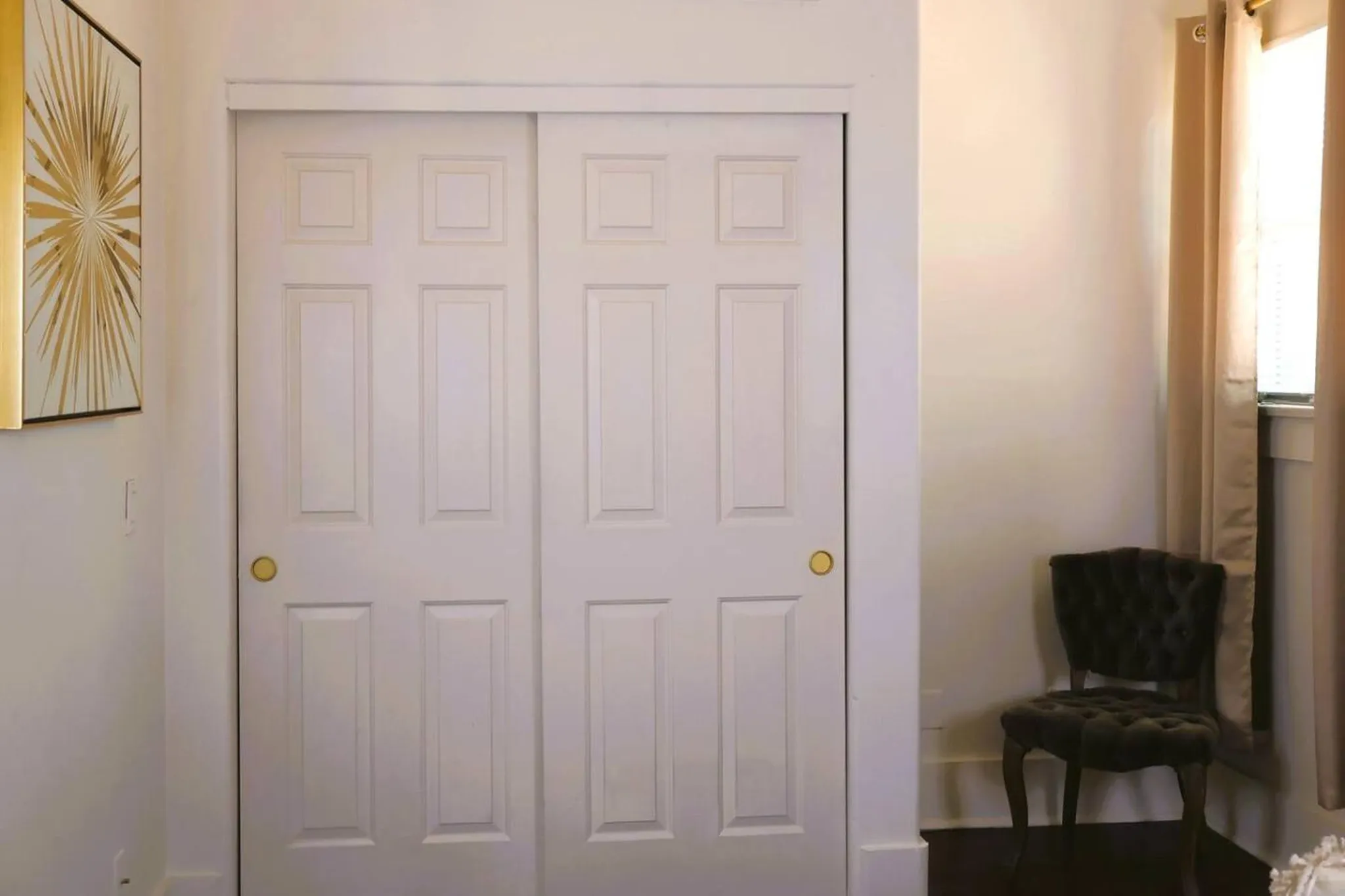 A white paneled closet with gold knobs.