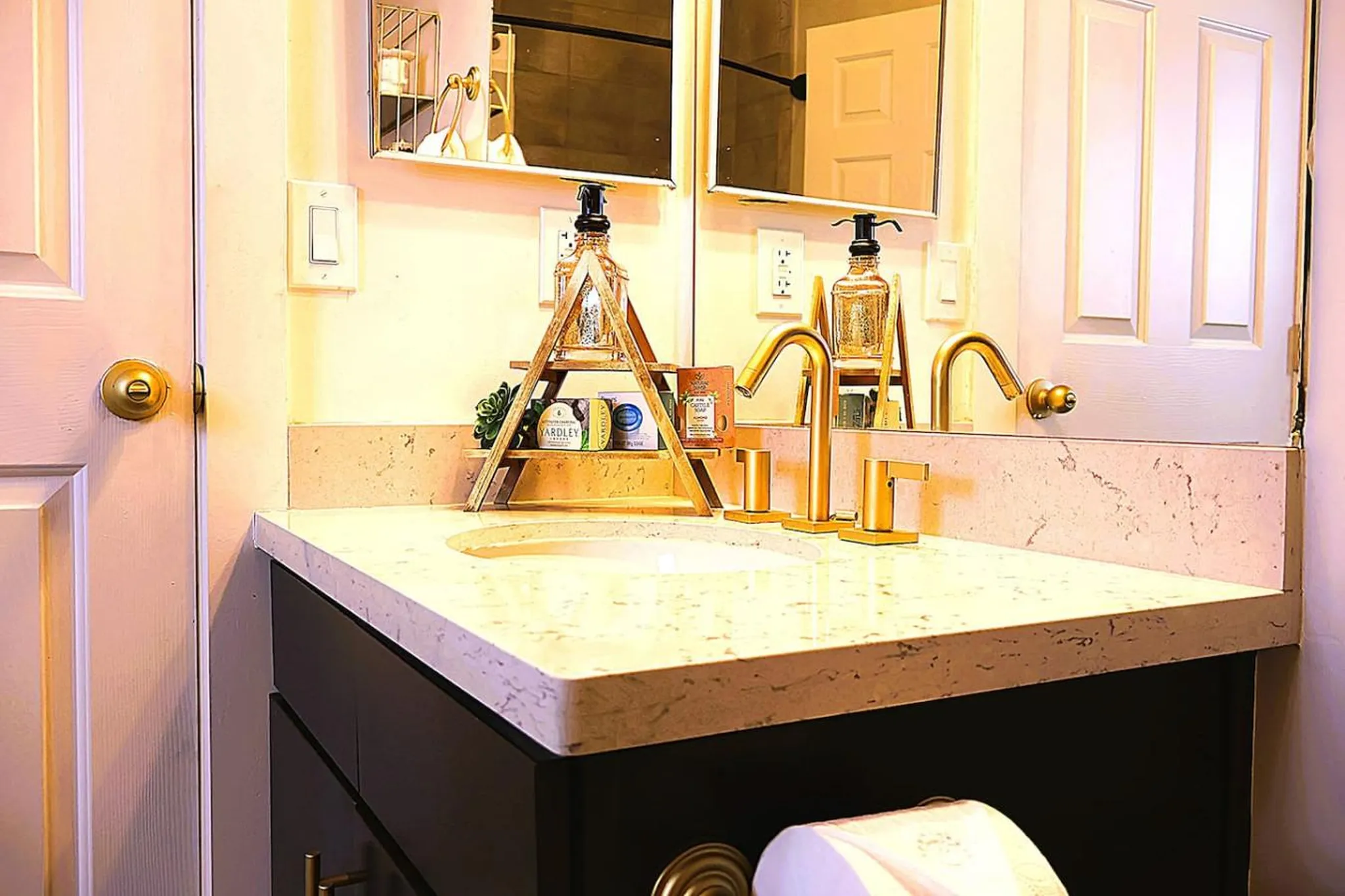 A bathroom vanity with a sink, gold faucet, and decor.