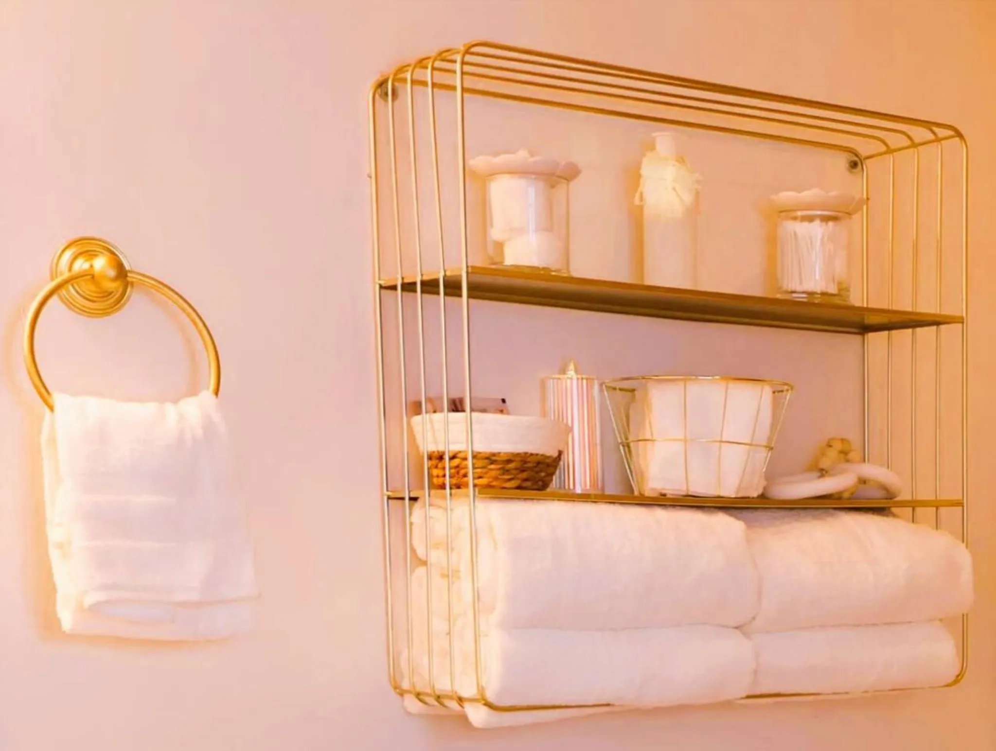 Gold bathroom shelf with towels and toiletries.