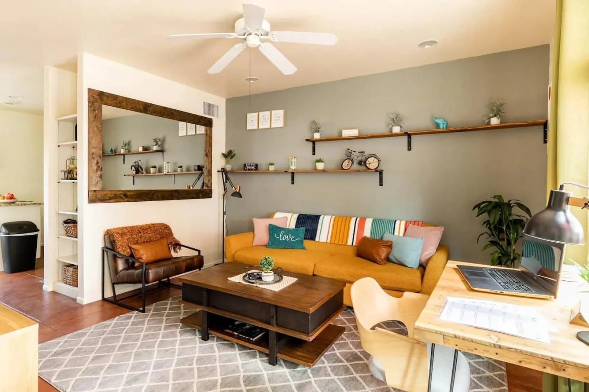 Living room with yellow sofa, brown armchair, coffee table, and shelves.