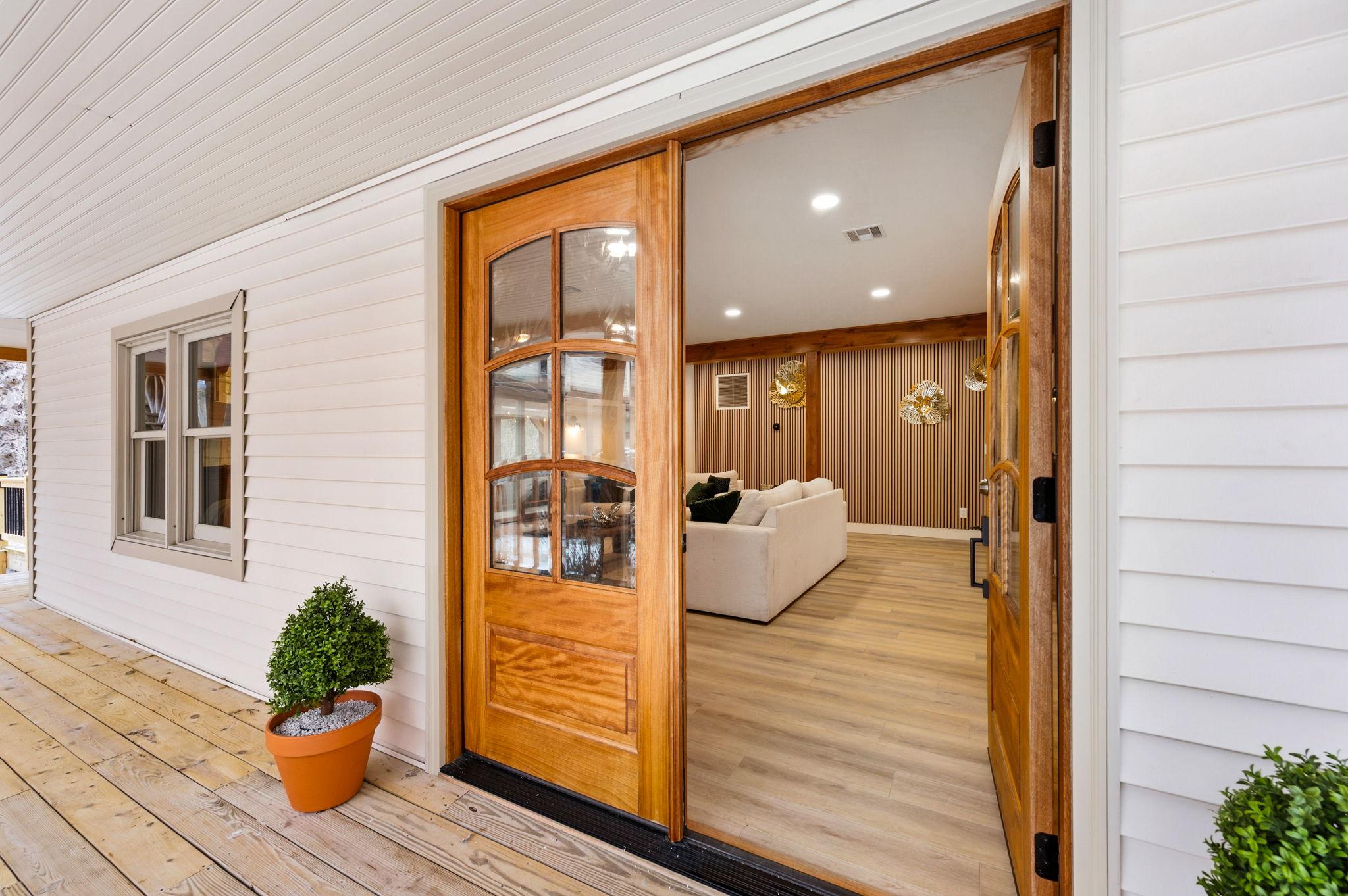 Front view of a wooden double door, opening to a living room with a white sofa.