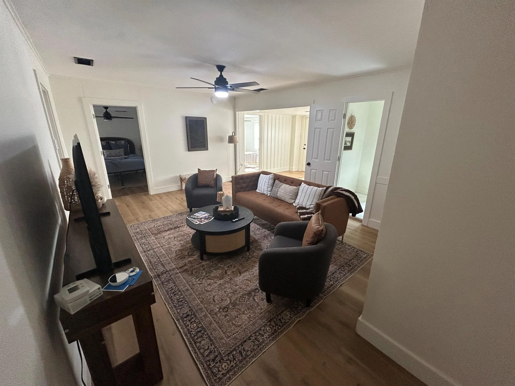 A living room features a brown sofa and chairs around a coffee table on a Persian rug.