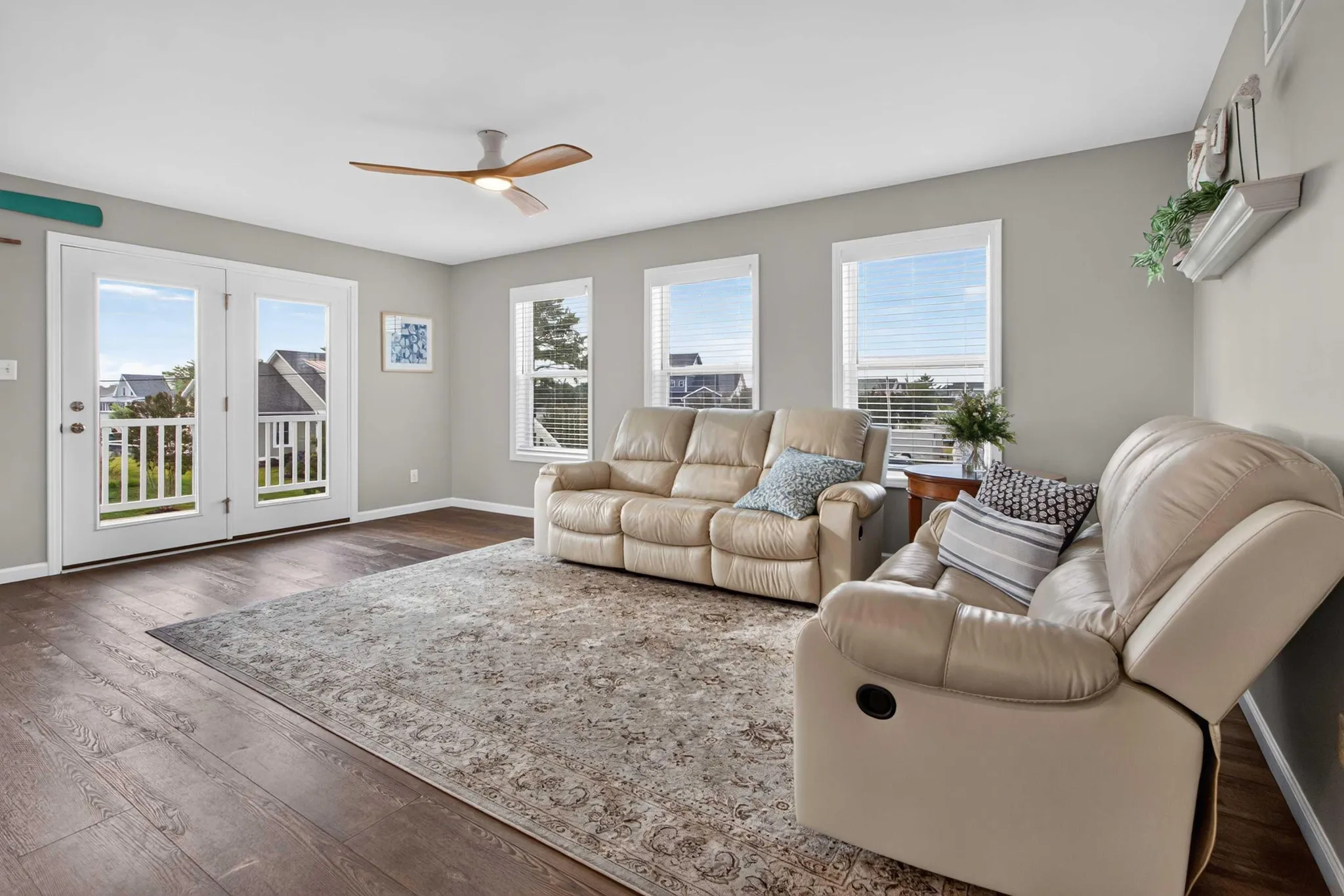 A living room with beige recliners, a patterned rug, and double doors leading outside.