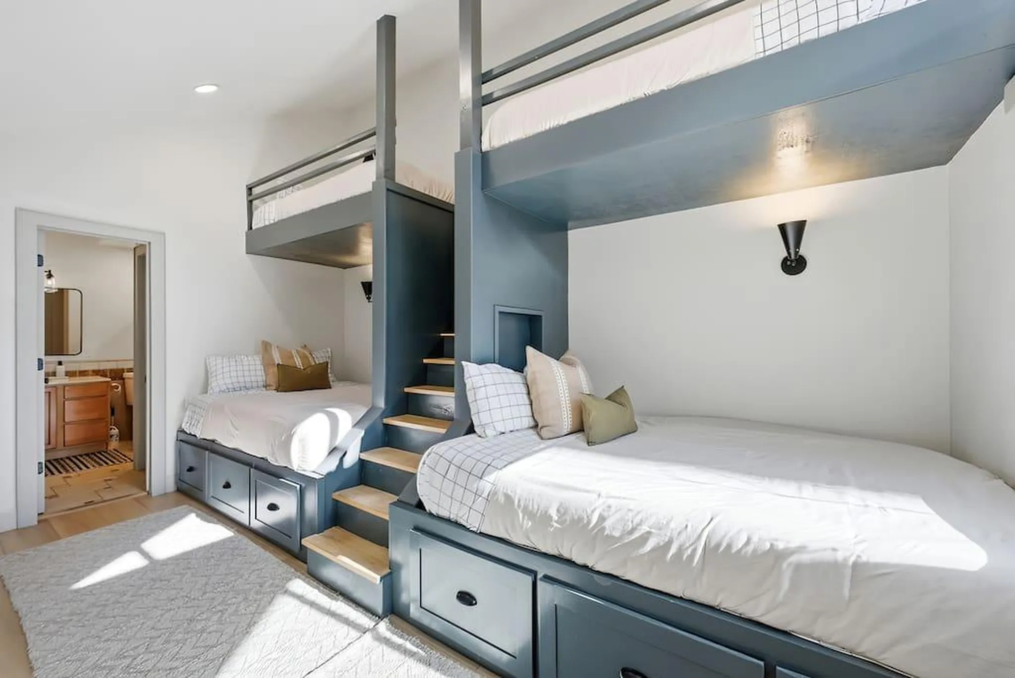 A bedroom with two bunk beds, each with lower beds and storage drawers.