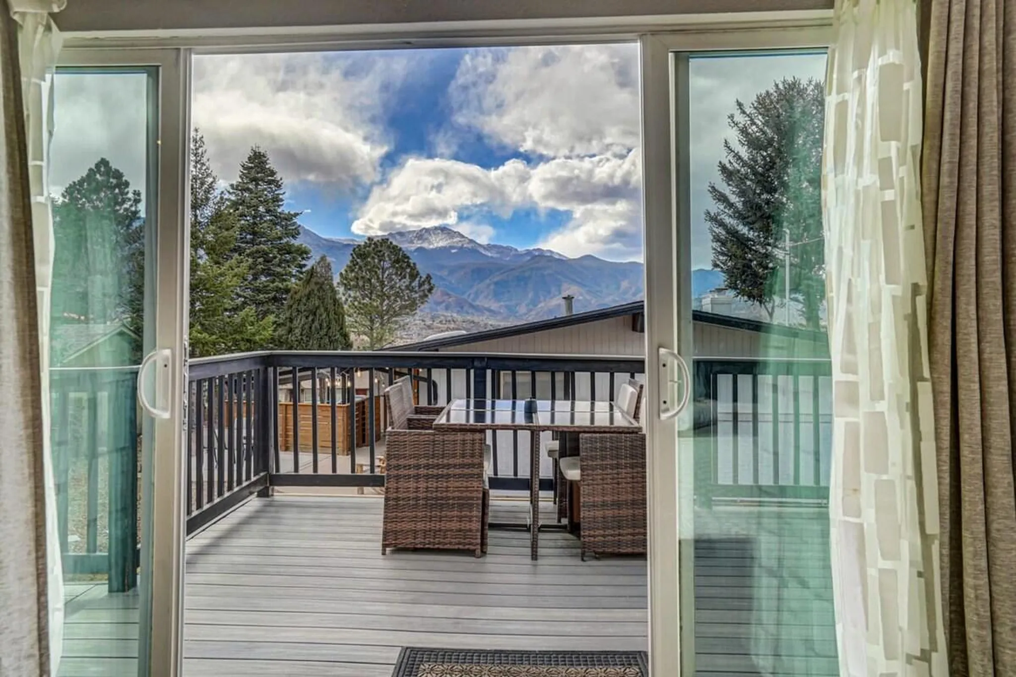 Inside view through open sliding glass door to a deck with outdoor dining and mountains.
