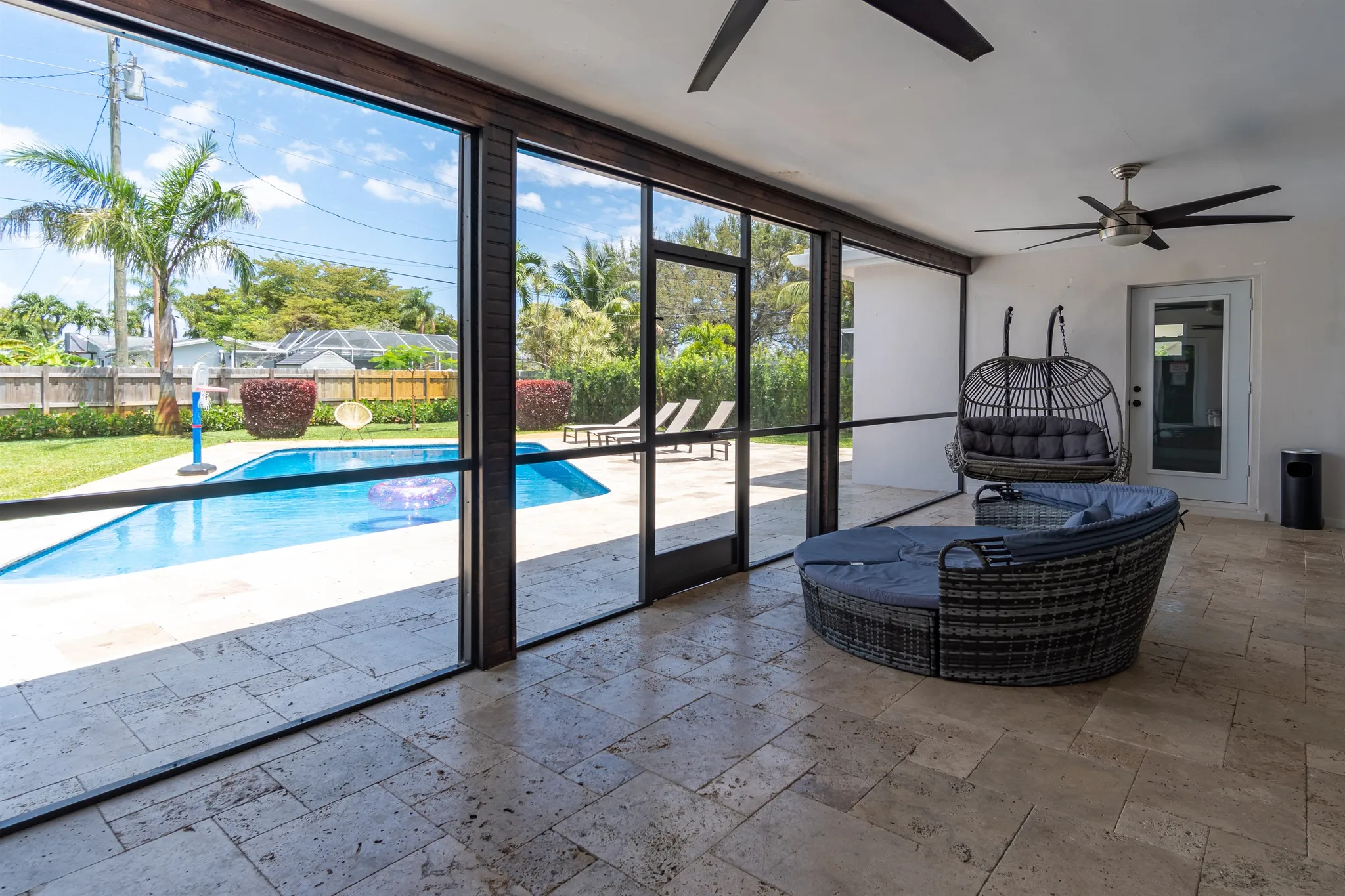 Covered patio with a hanging chair beside the pool