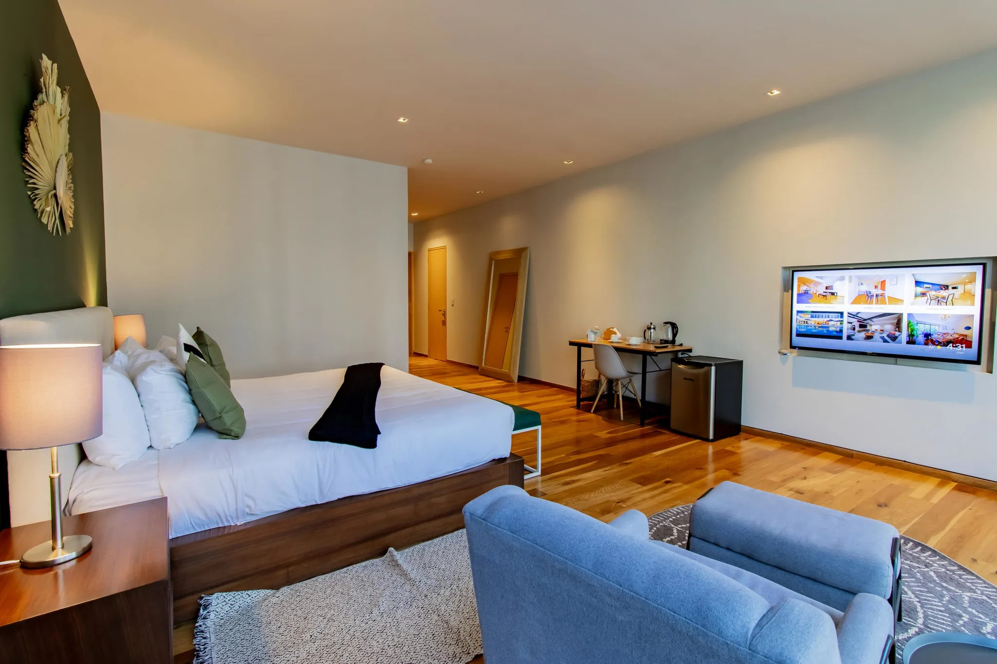 A modern hotel room with a bed, chairs, a desk, and a TV.