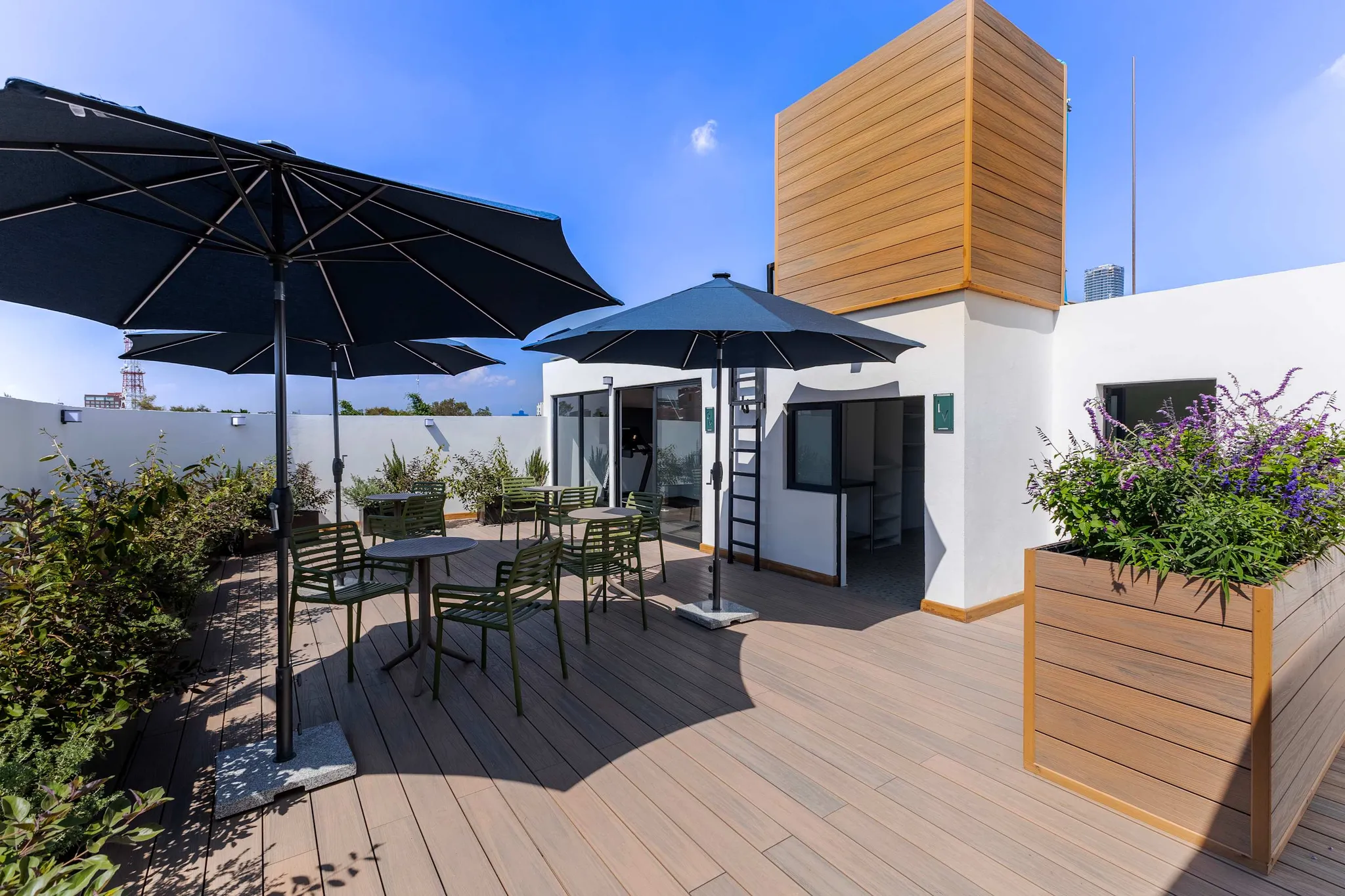 Rooftop terrace with seating, umbrellas, plants, and a wooden structure.