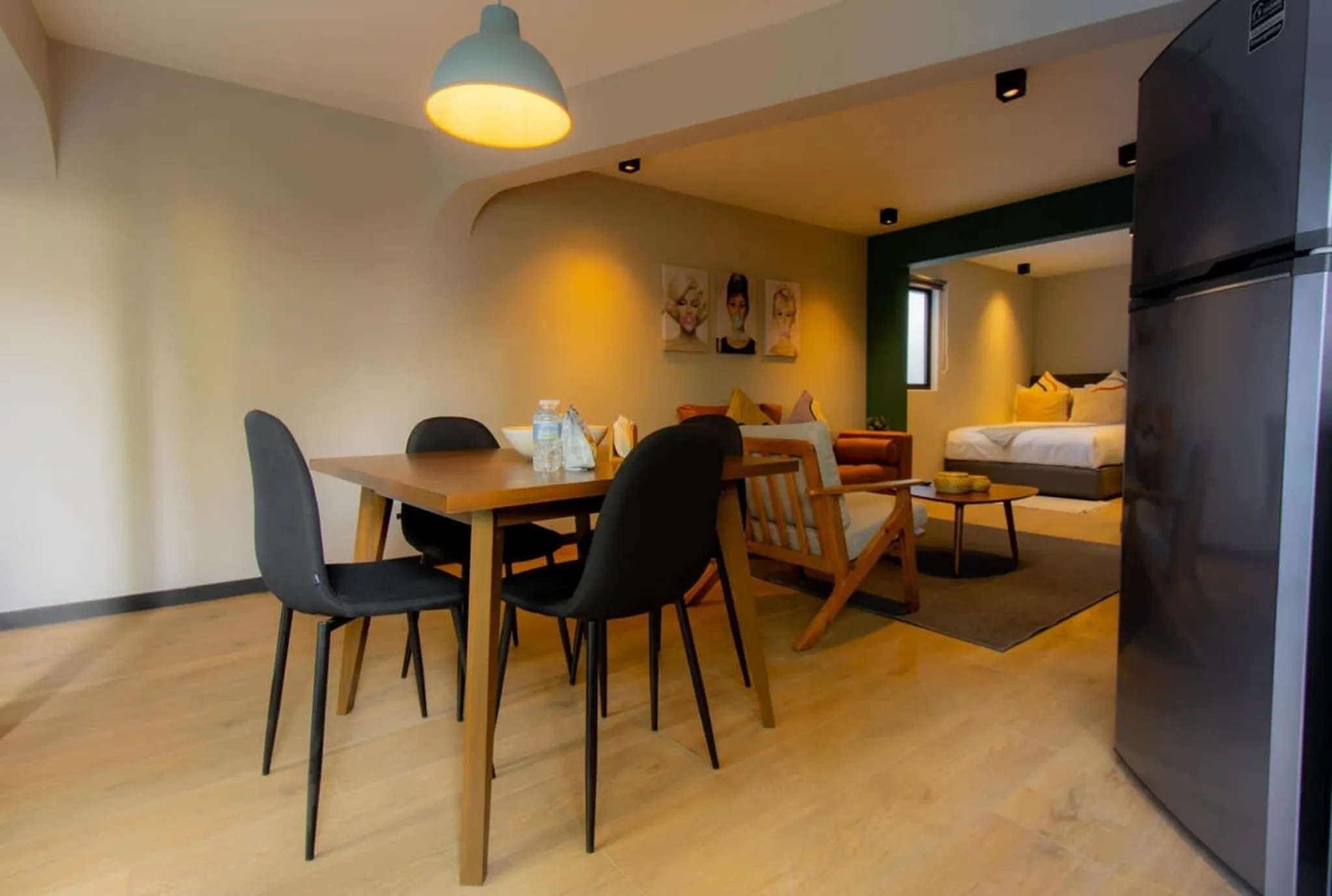 A modern living room with a dining table, chairs, and a bed.