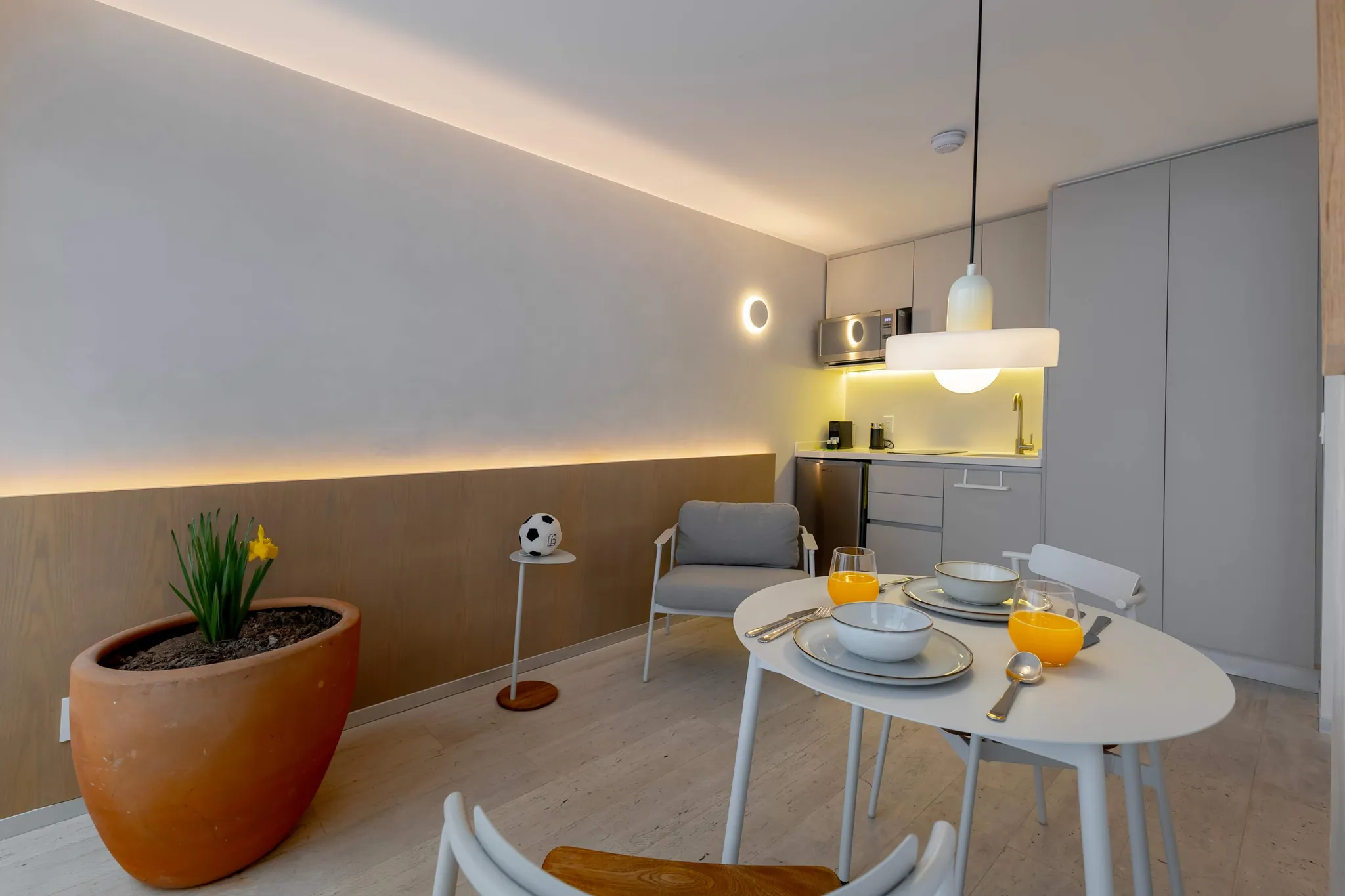 Interior shot of a modern dining area with a white table, chairs, and kitchen.