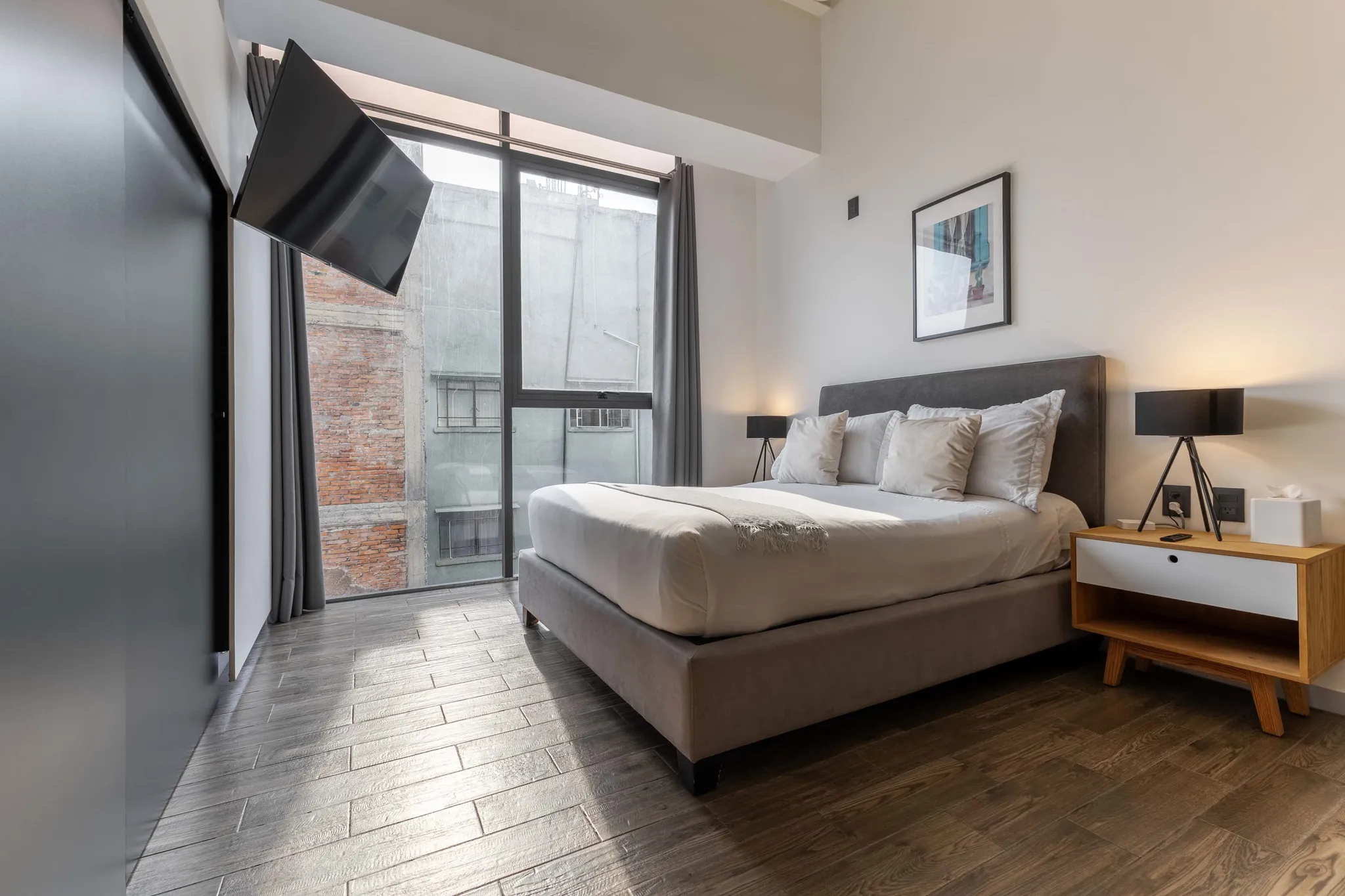 A modern bedroom with a bed, nightstand, and TV.