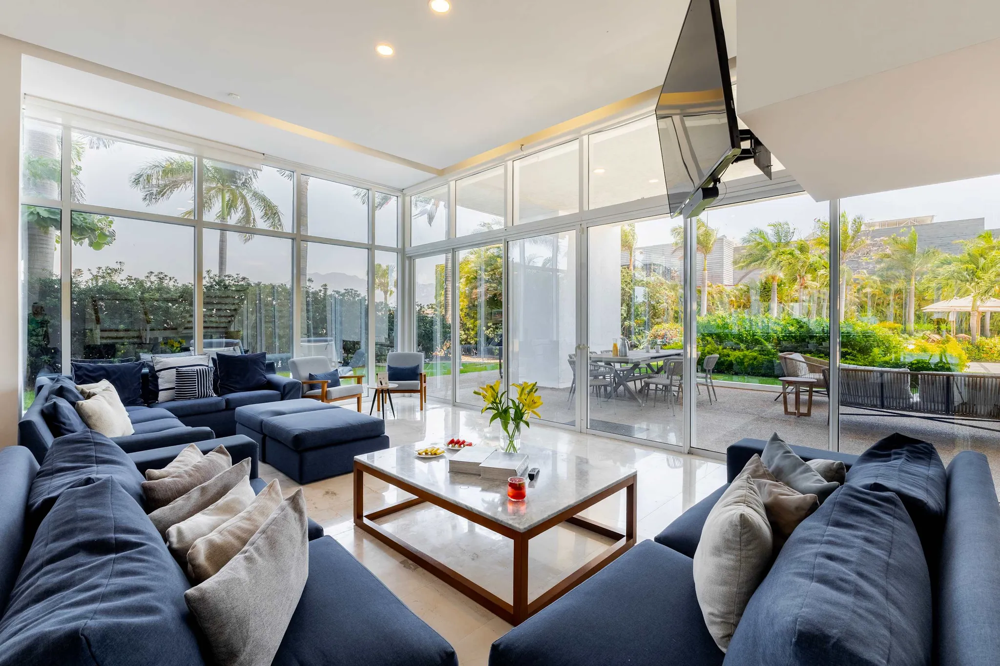 A spacious living room with large windows, a sectional sofa, and outdoor seating.
