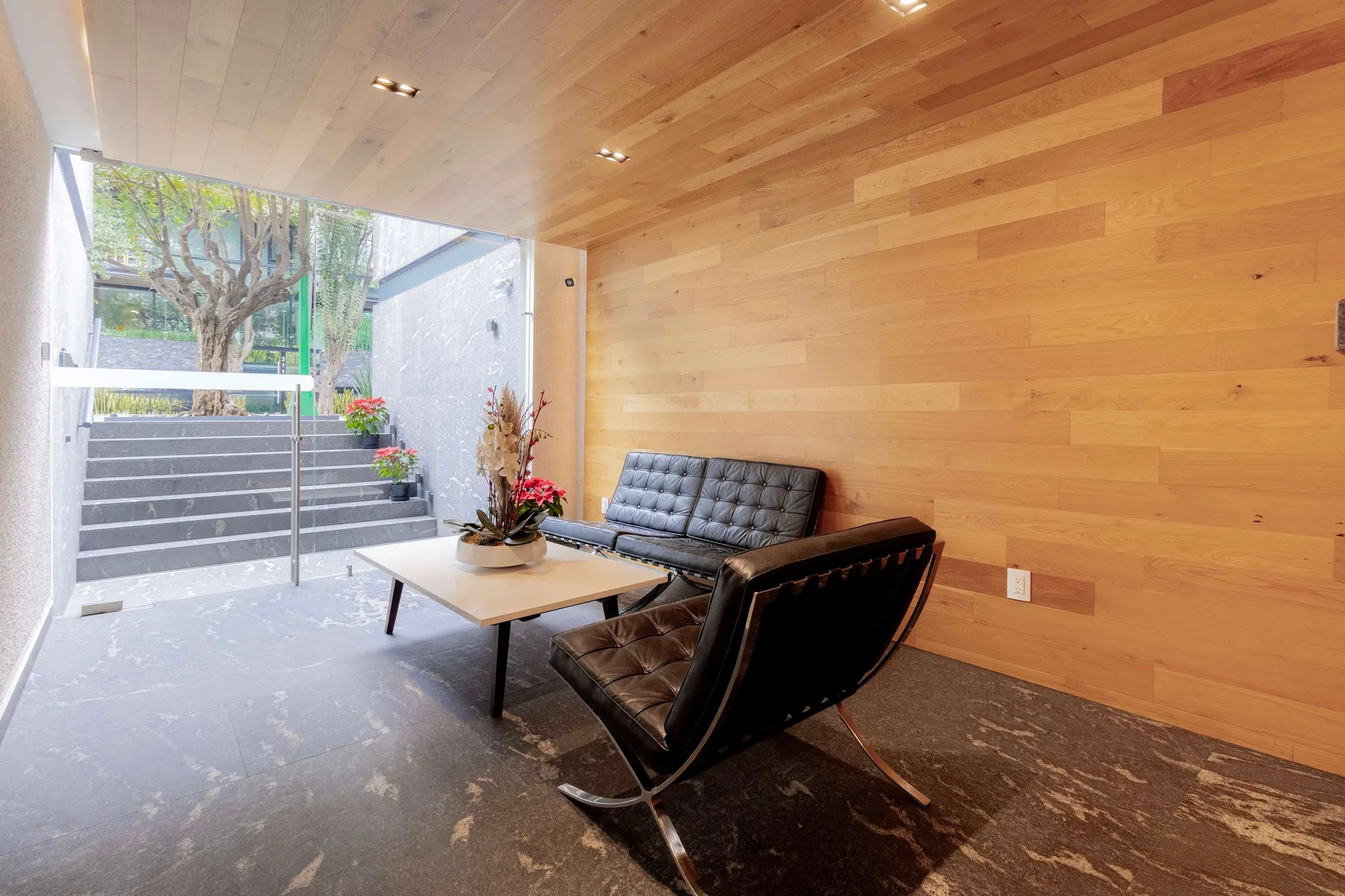 Wood-paneled reception lounge with black leather seating at Galileo Residences.