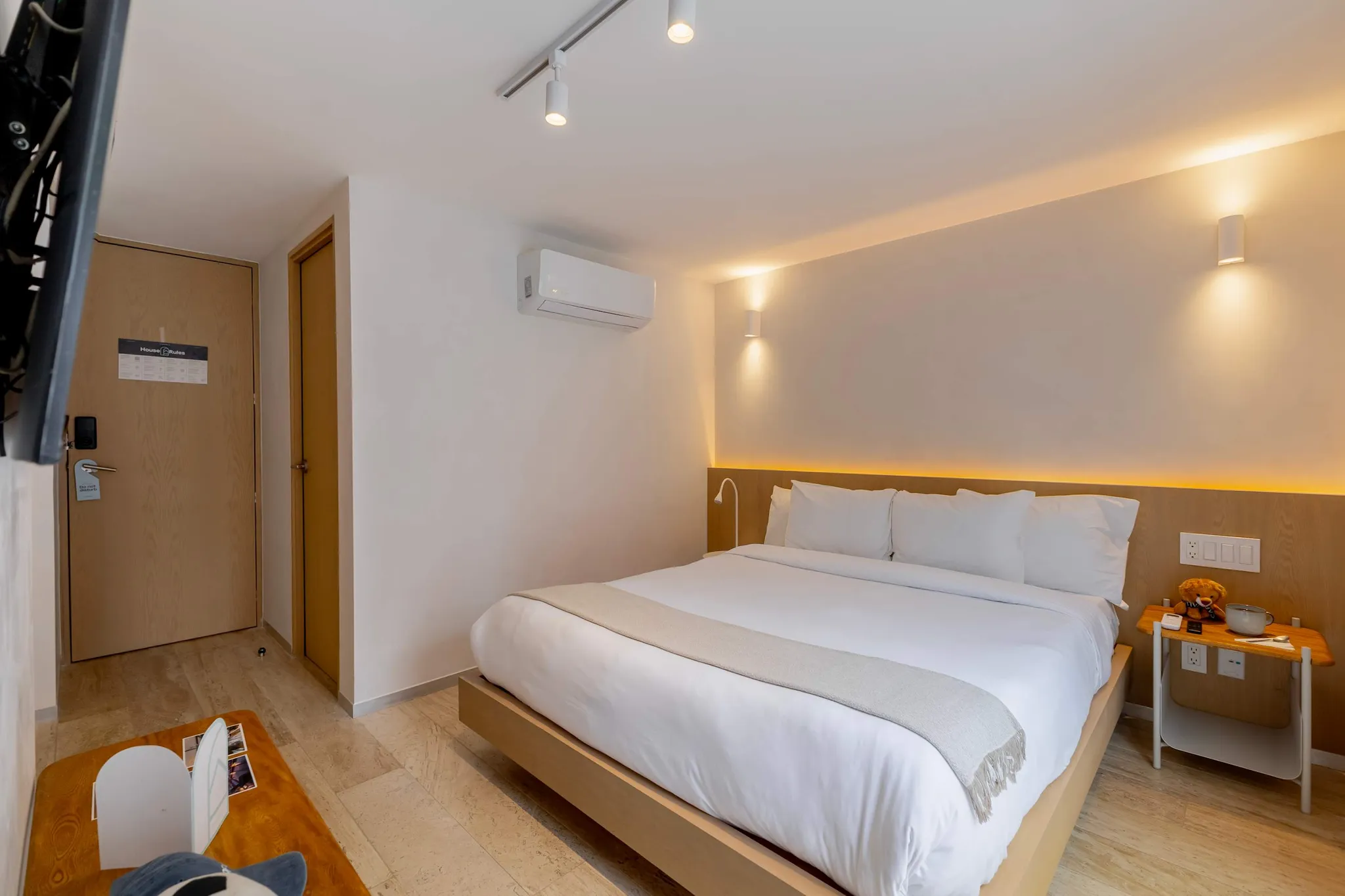 A modern hotel room with a king-size bed, air conditioning, and a wooden headboard.