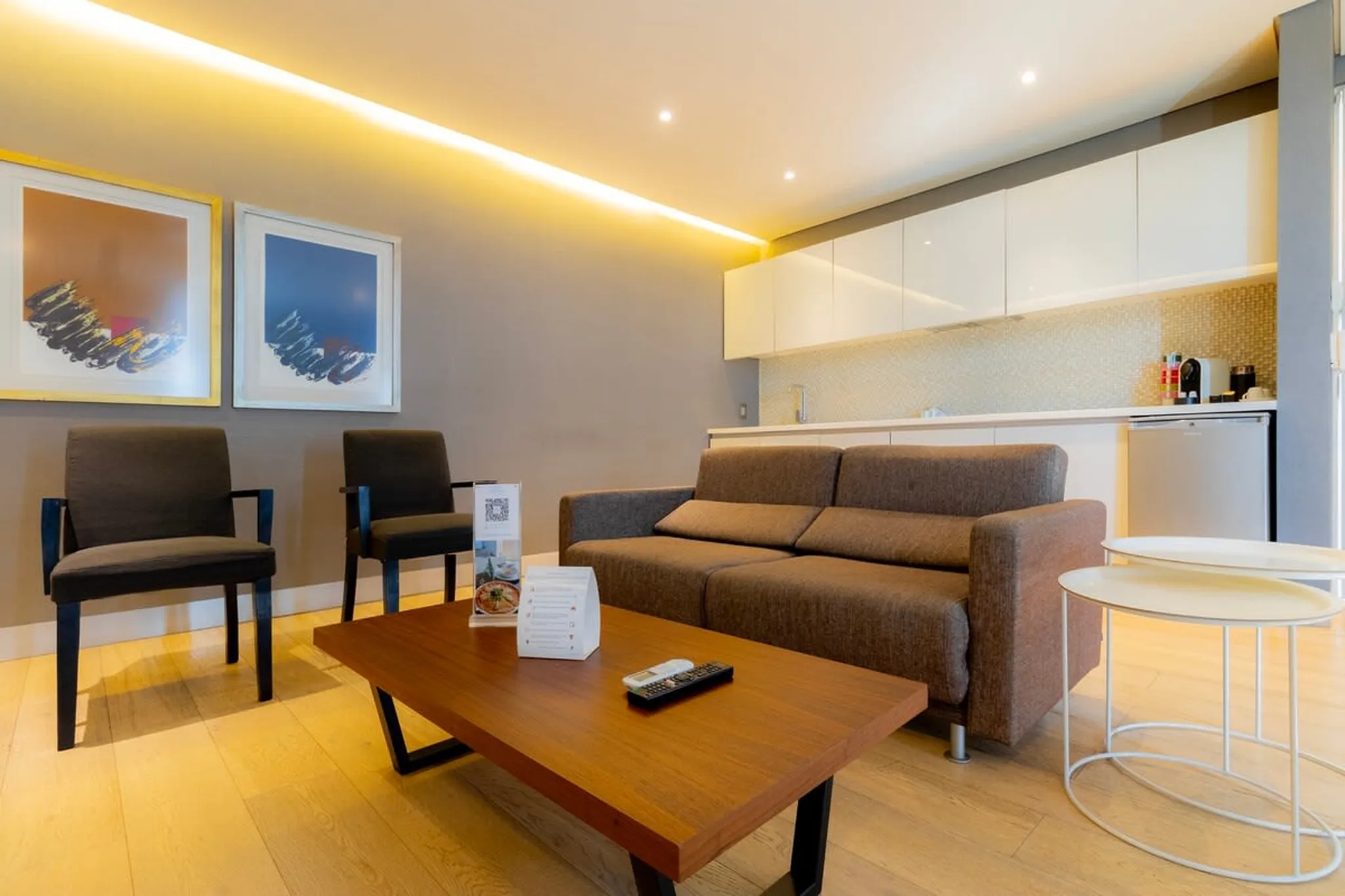 A modern living room with a sofa, chairs, coffee table, and kitchen.