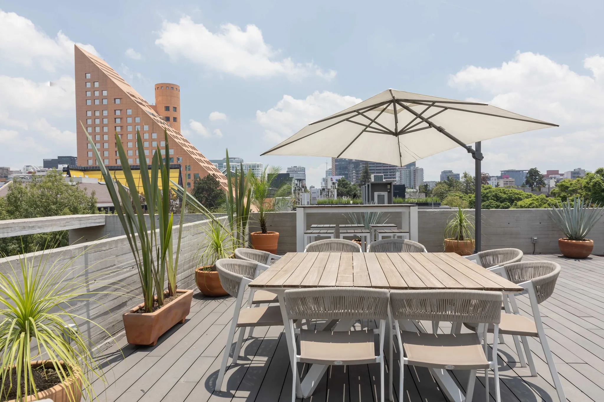 A rooftop patio with a dining set and city view.