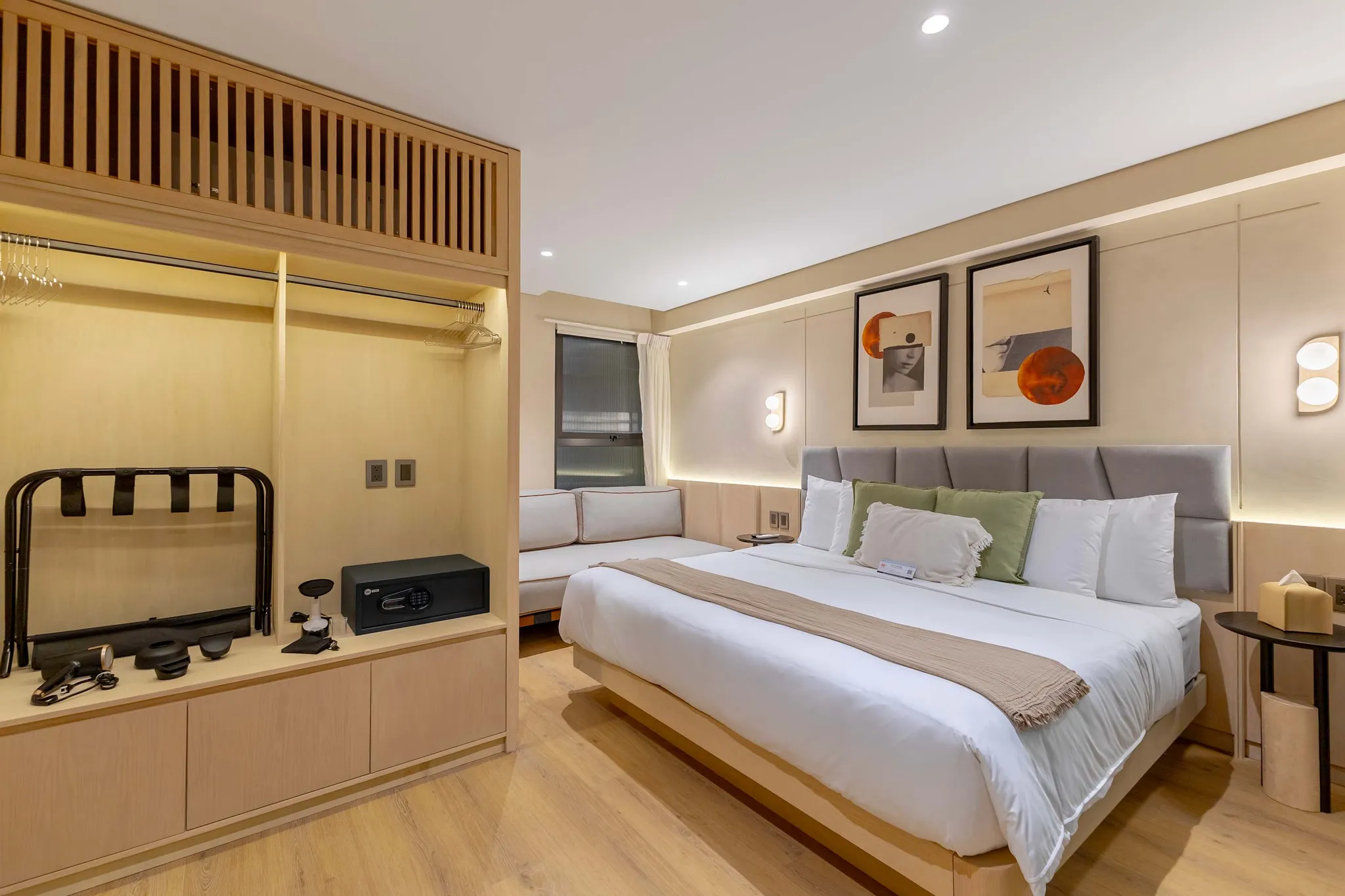 A modern hotel room with a king-size bed, couch, and open closet.