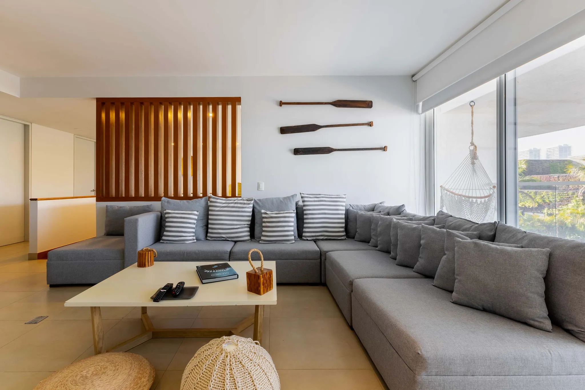A sectional sofa with grey upholstery, striped pillows, and a coffee table in a bright, modern livin