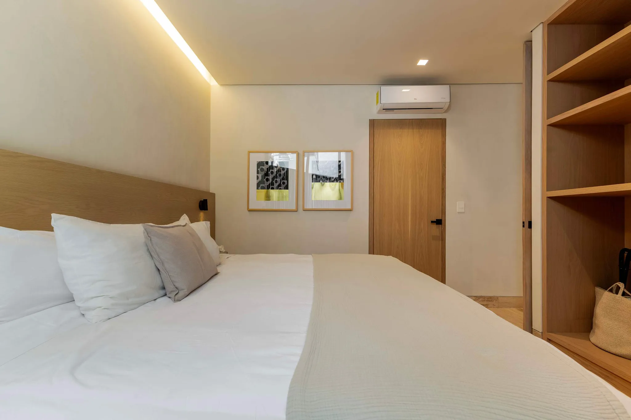 Modern bedroom with a white bed, wood accents, and a large closet.