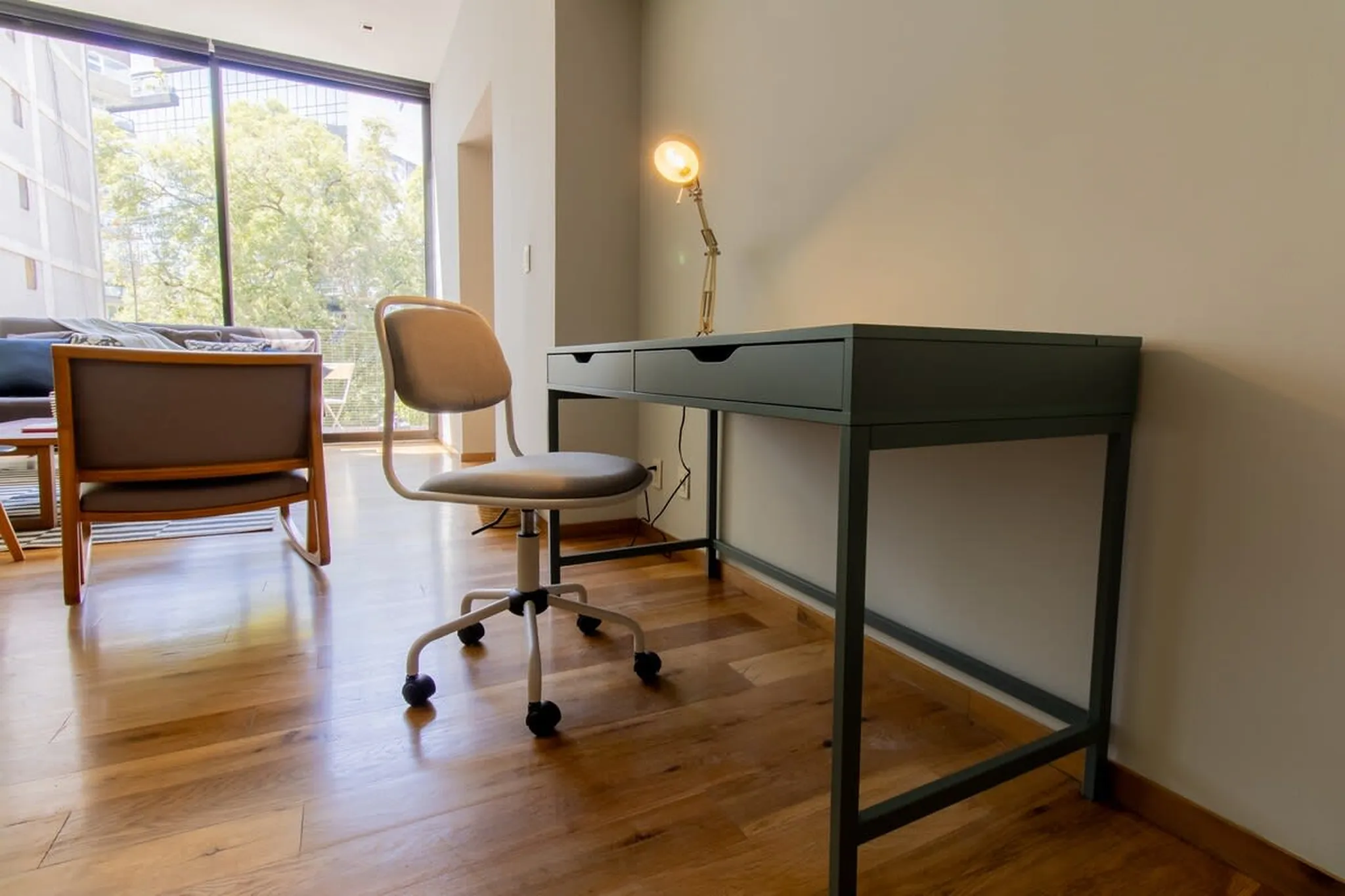 A gray desk chair and a dark gray desk sit on a wooden floor.