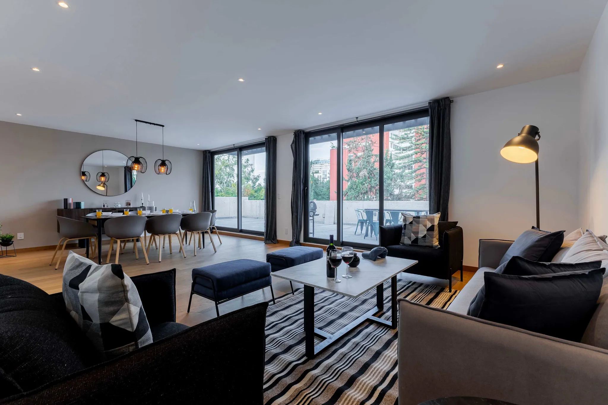 Modern living and dining room with large windows and a balcony.