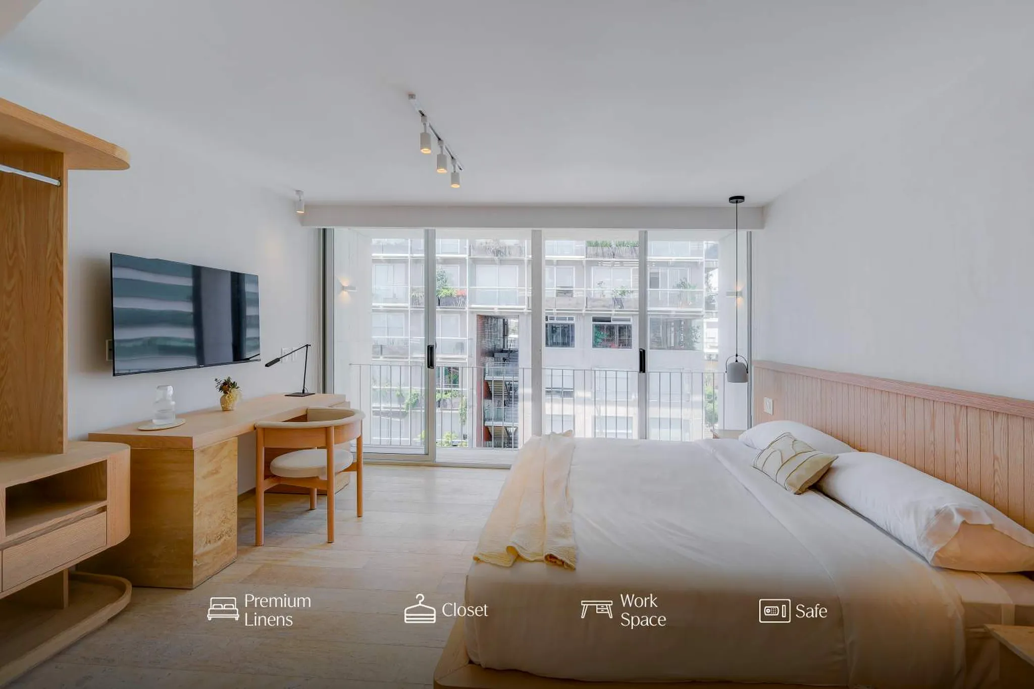 Bedroom with desk, TV, and large window overlooking city.