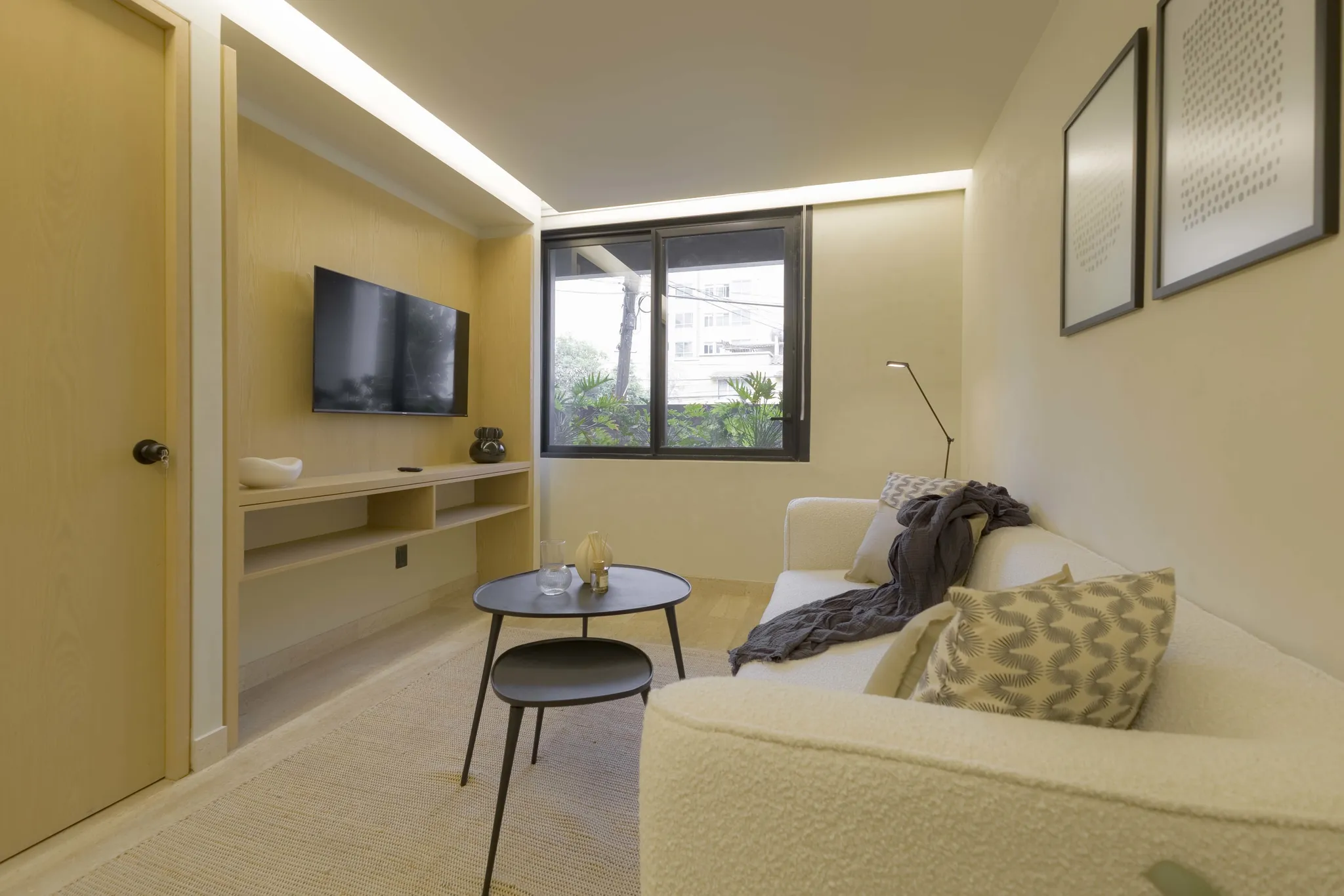 A modern living room with a cream sofa, black coffee table, and tv.