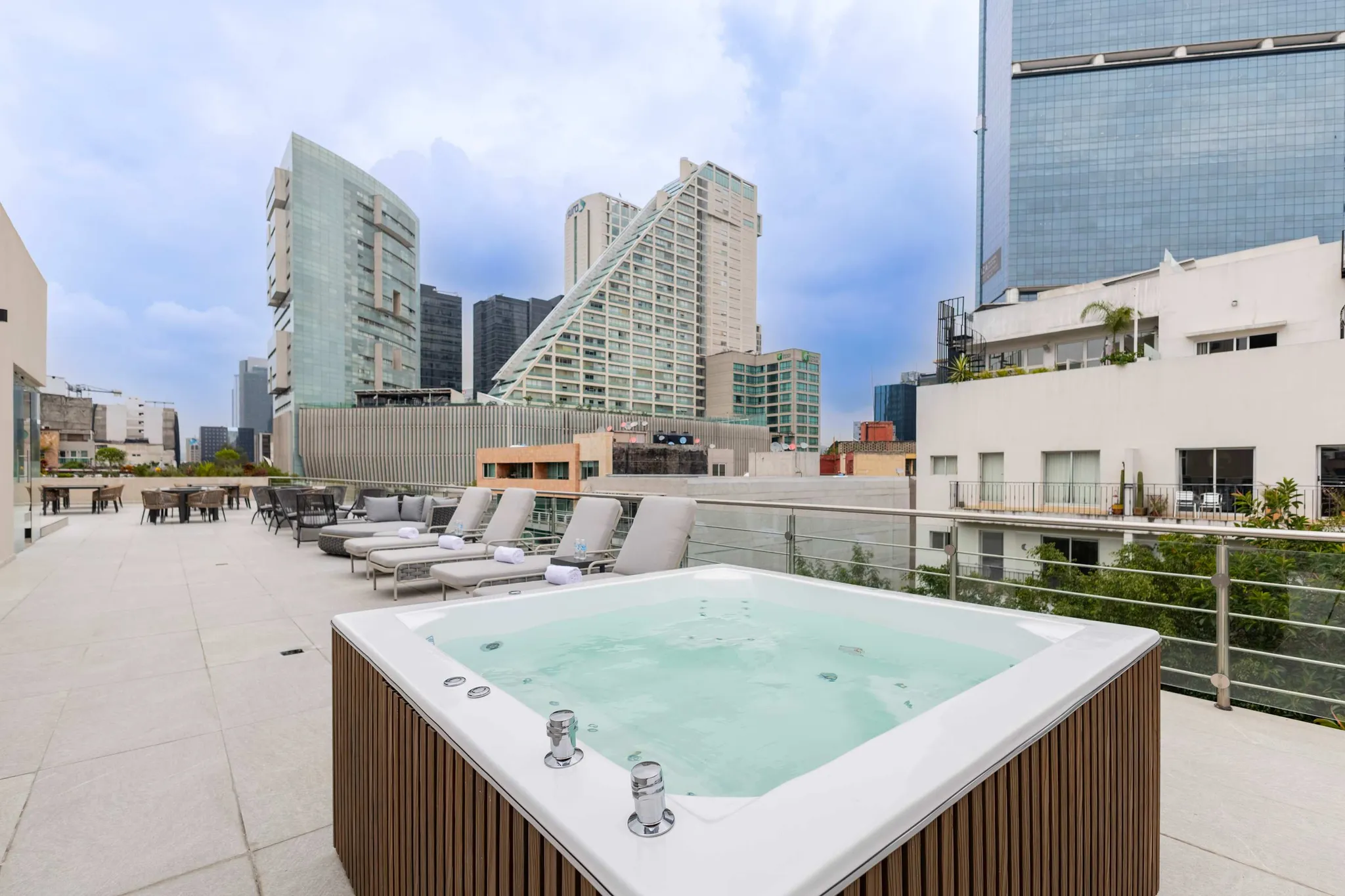 Rooftop hot tub with lounge chairs and city skyline view.