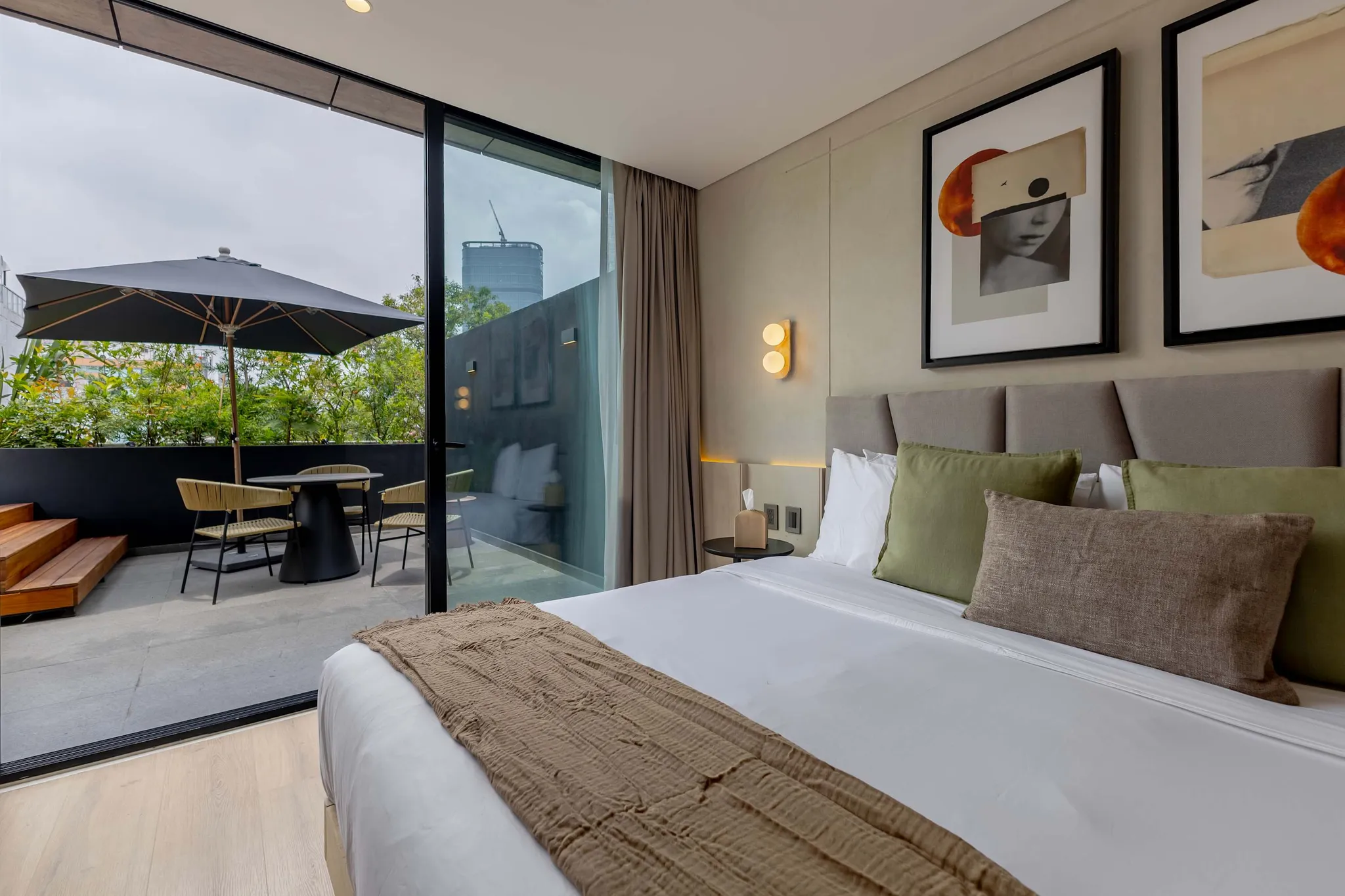A modern bedroom with a bed, artwork, and a patio with a table and chairs.