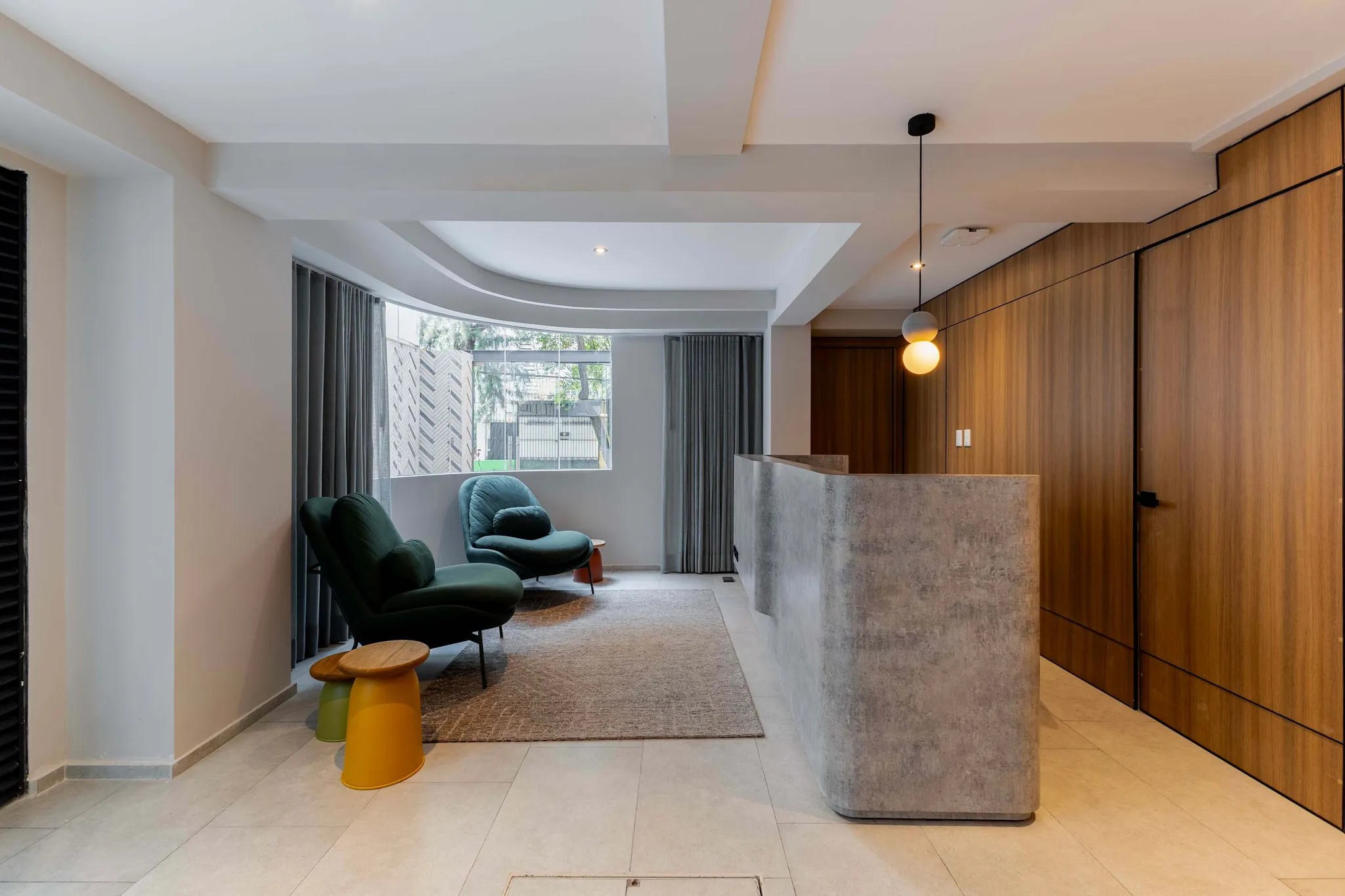 Modern reception area with green chairs, a concrete desk, and wood paneling at a Capitalia building.