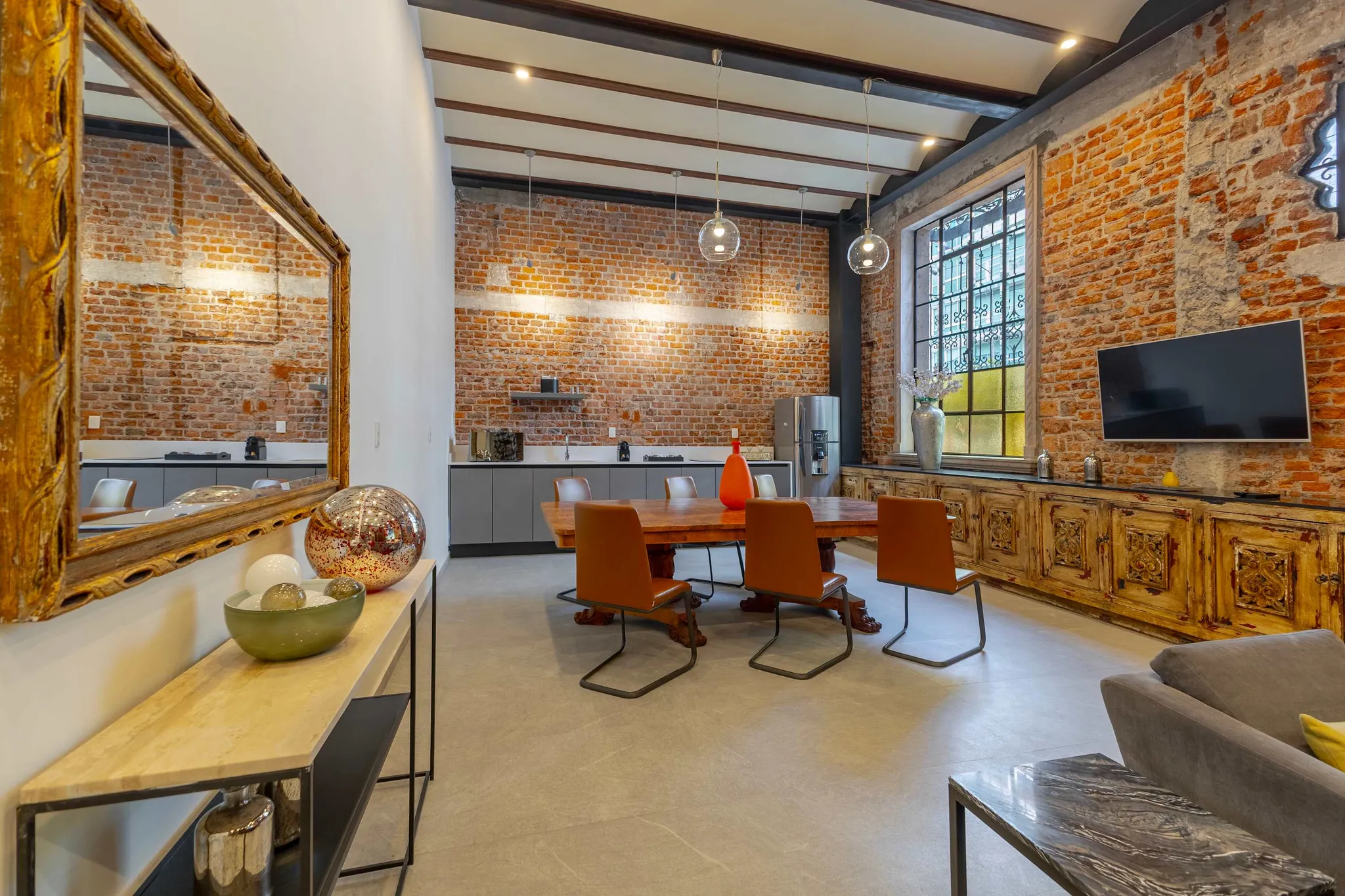 A dining room with a wooden table, leather chairs, and exposed brick walls.