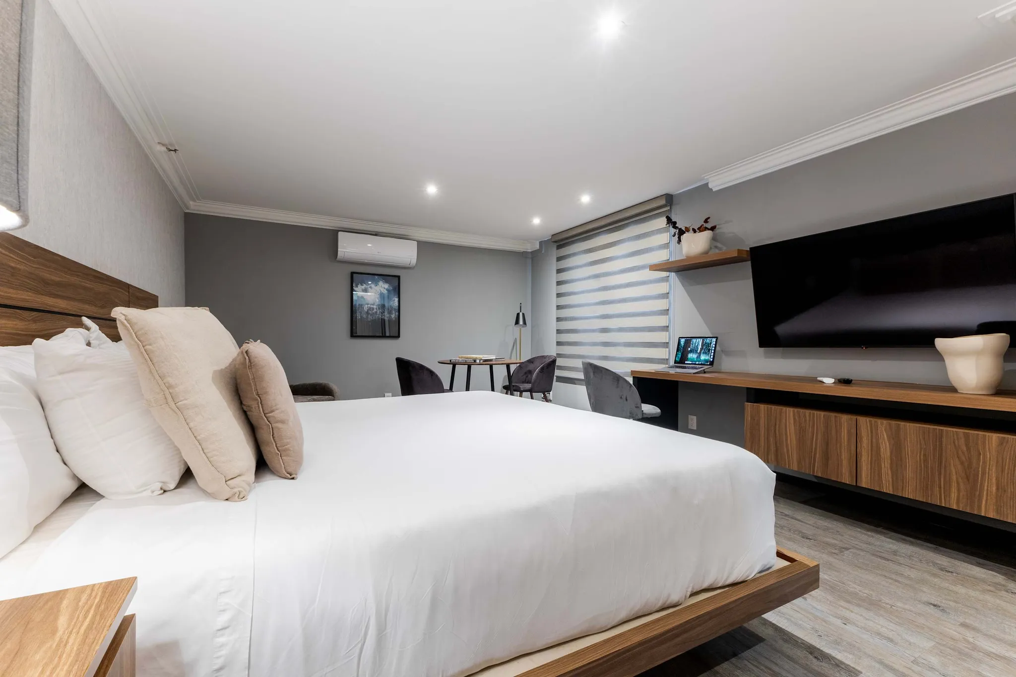 Modern hotel room with a large bed, TV, and a work desk.