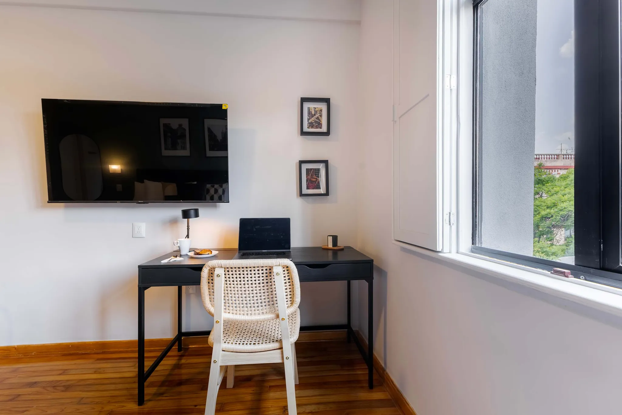 A modern room with a desk, chair, television, and a window with blinds.